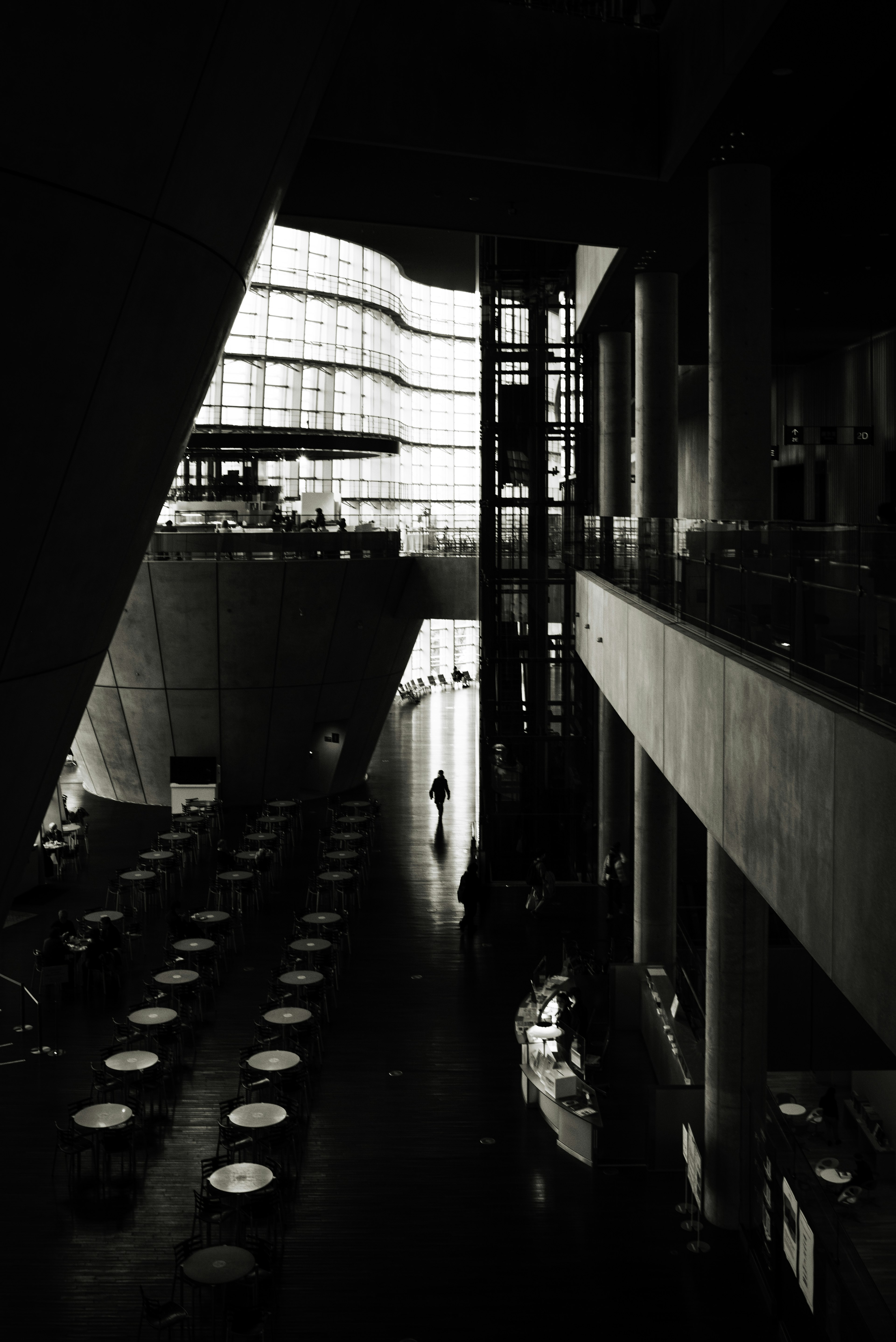 Intérieur d'un bâtiment moderne avec un contraste noir et blanc frappant comportant de nombreuses tables et des murs en verre