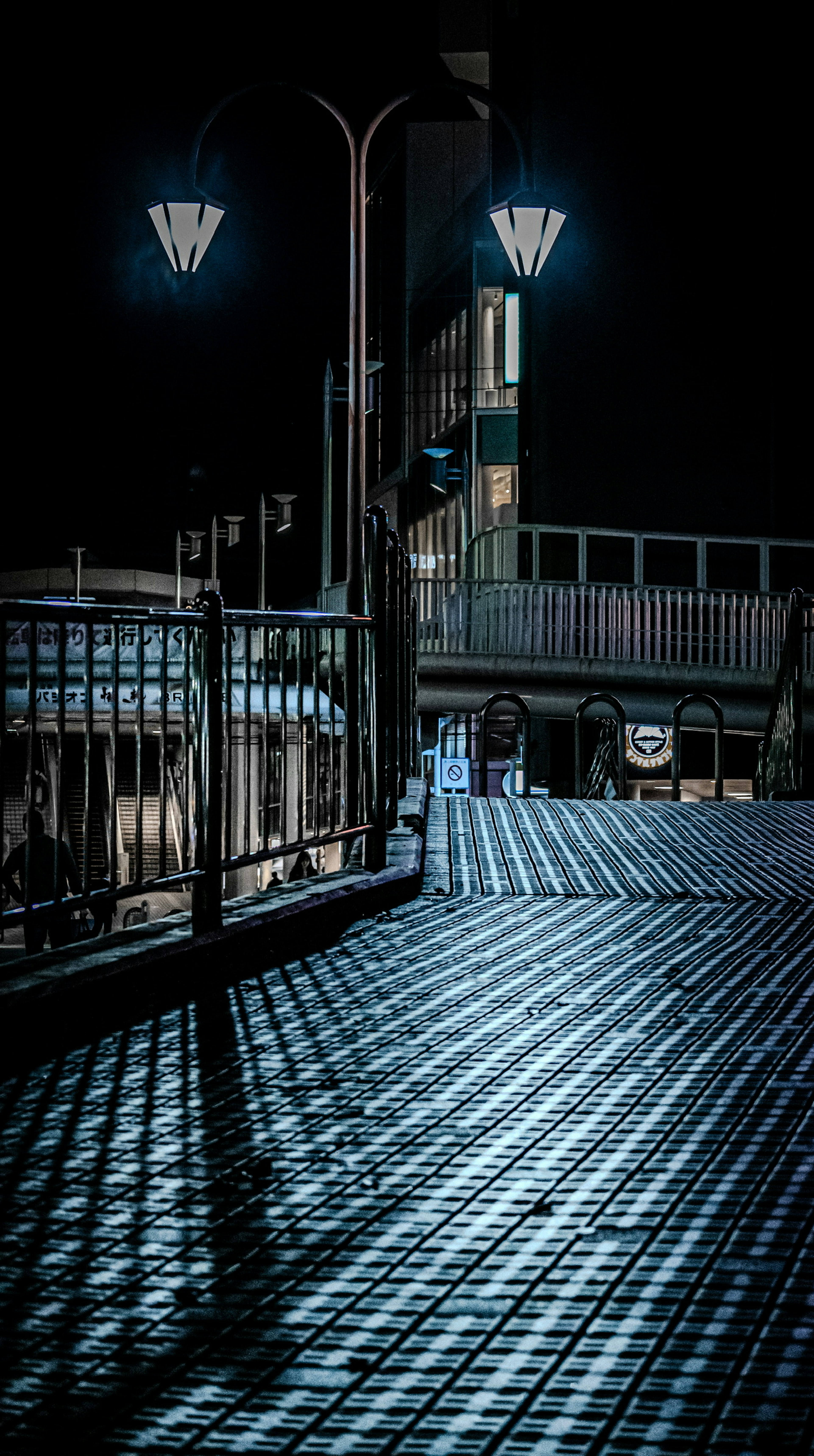 Quiet sidewalk scene illuminated by street lamps at night