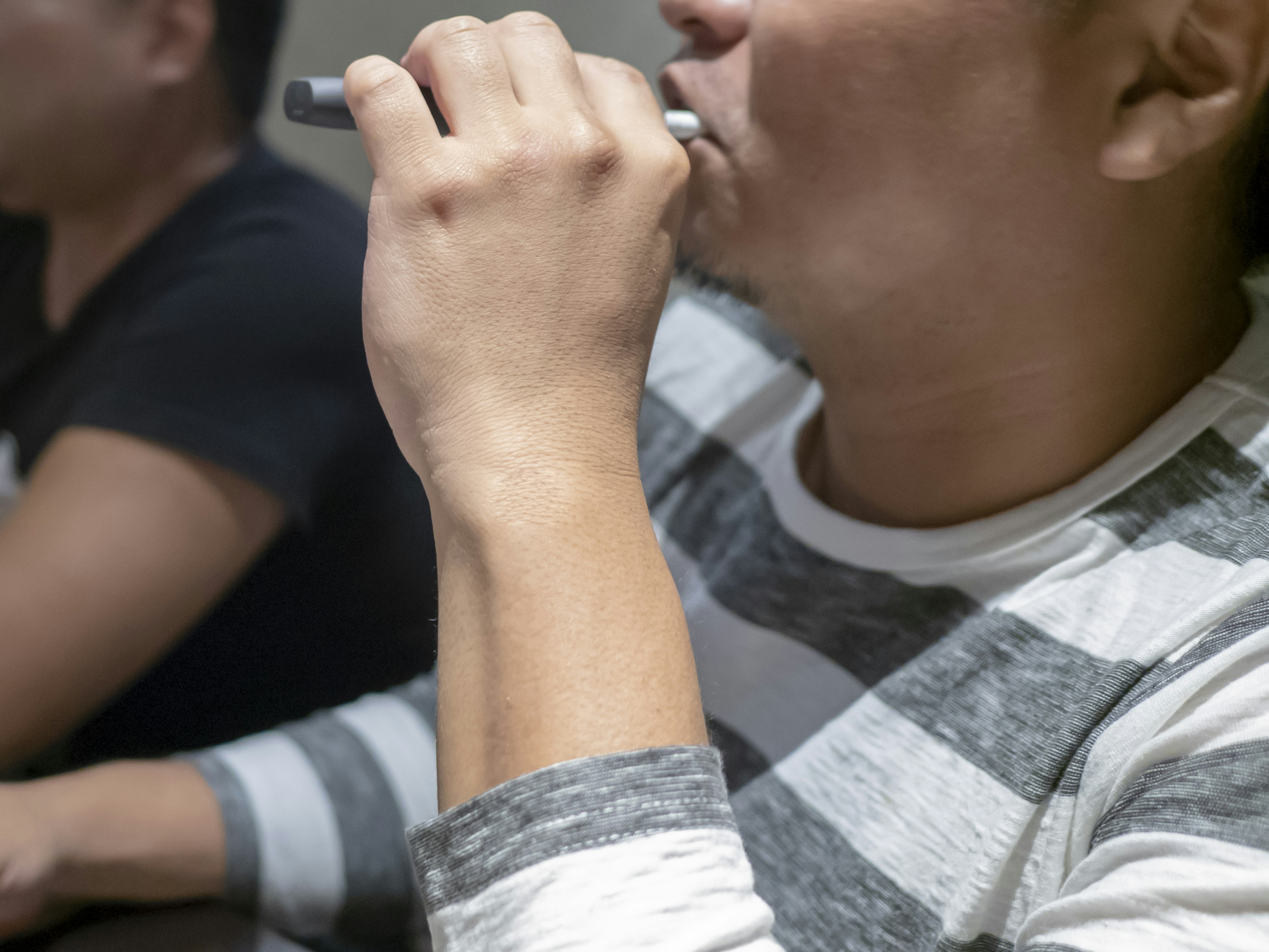 Homme en chemise rayée tenant un stylo à la bouche