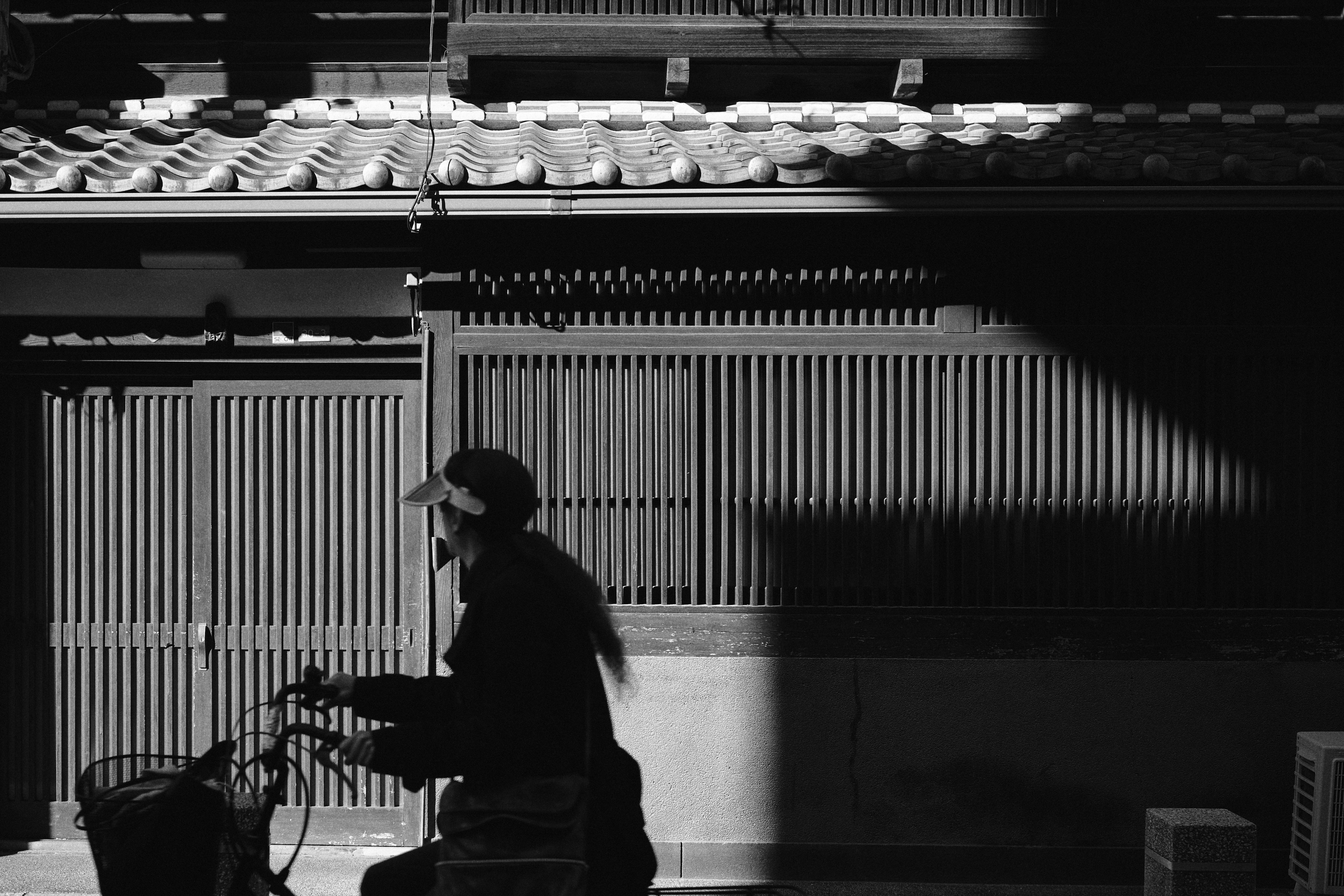 Silhouette of a person riding a bicycle against a backdrop of traditional architecture