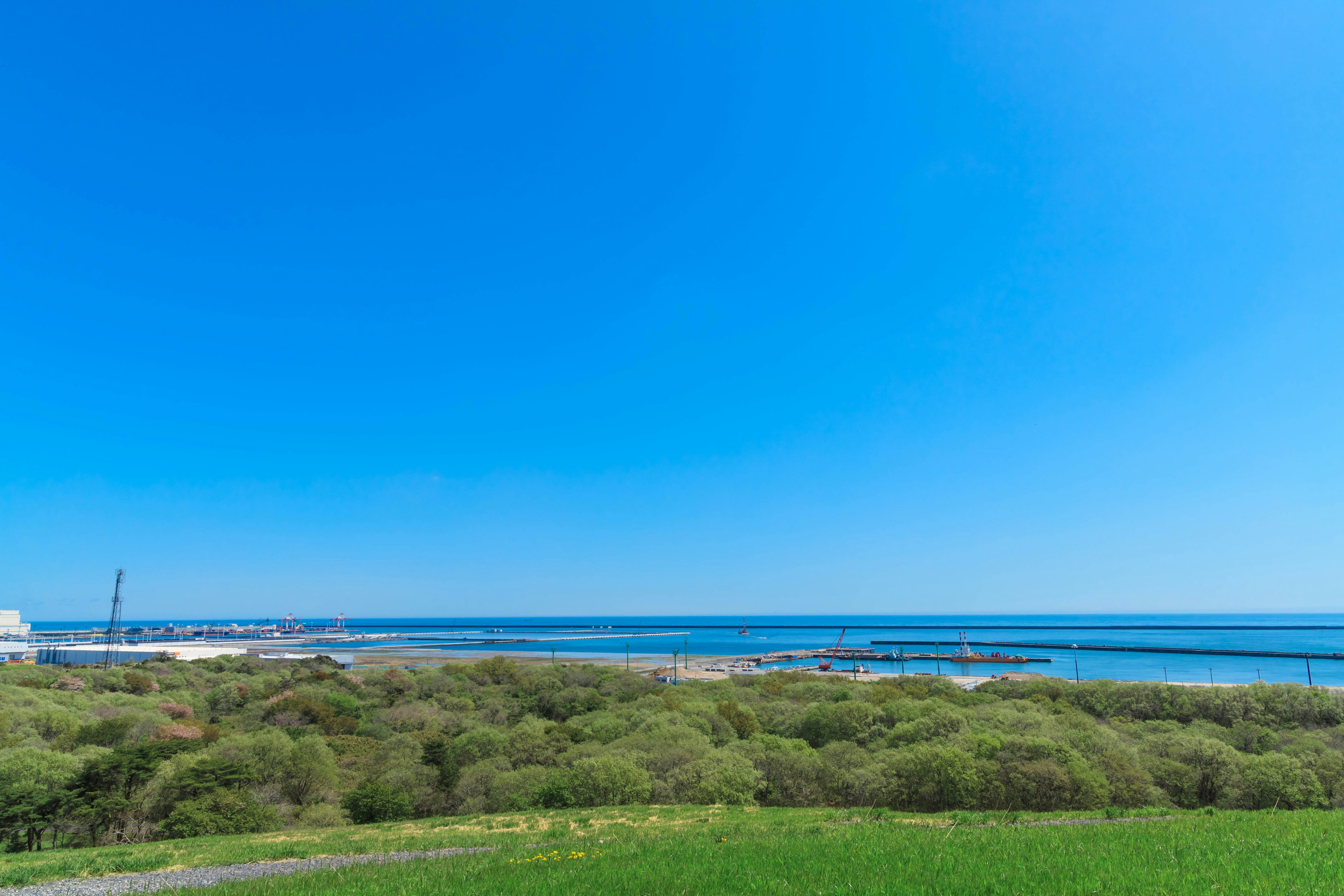 Vista escénica de colinas verdes bajo un cielo azul claro y océano