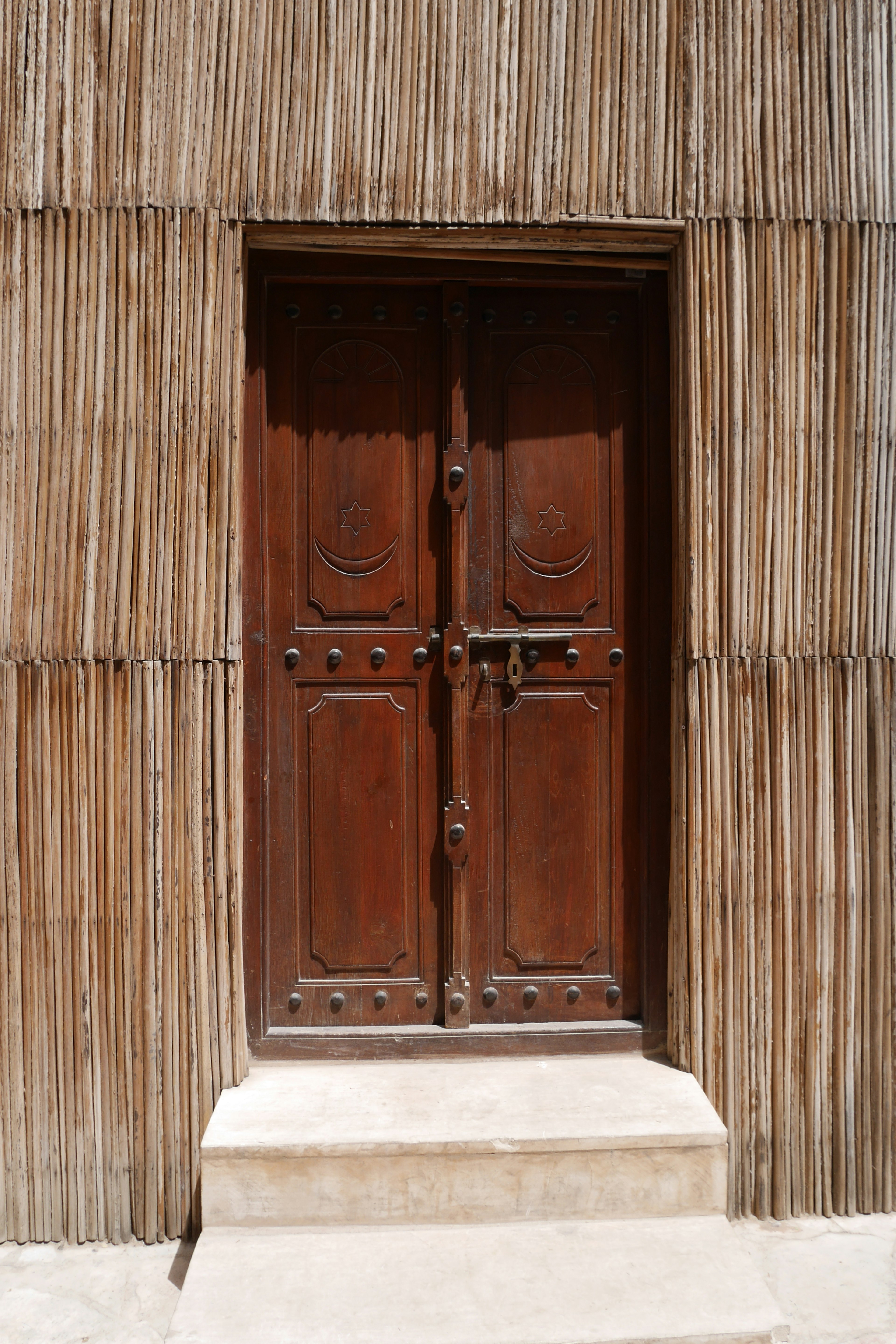 A wooden door set within a thatched wall