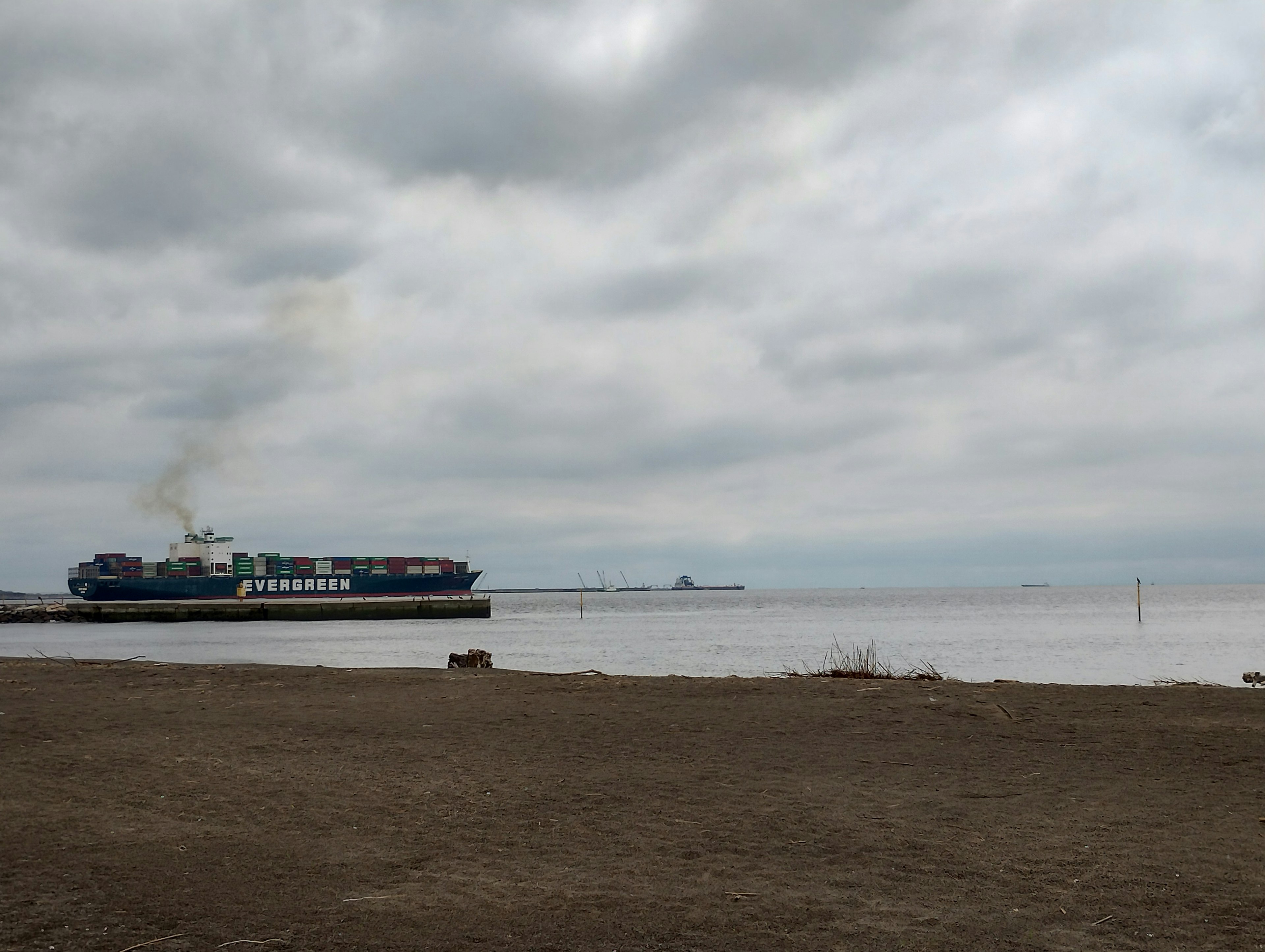 A ship docked under a cloudy sky with a calm sea