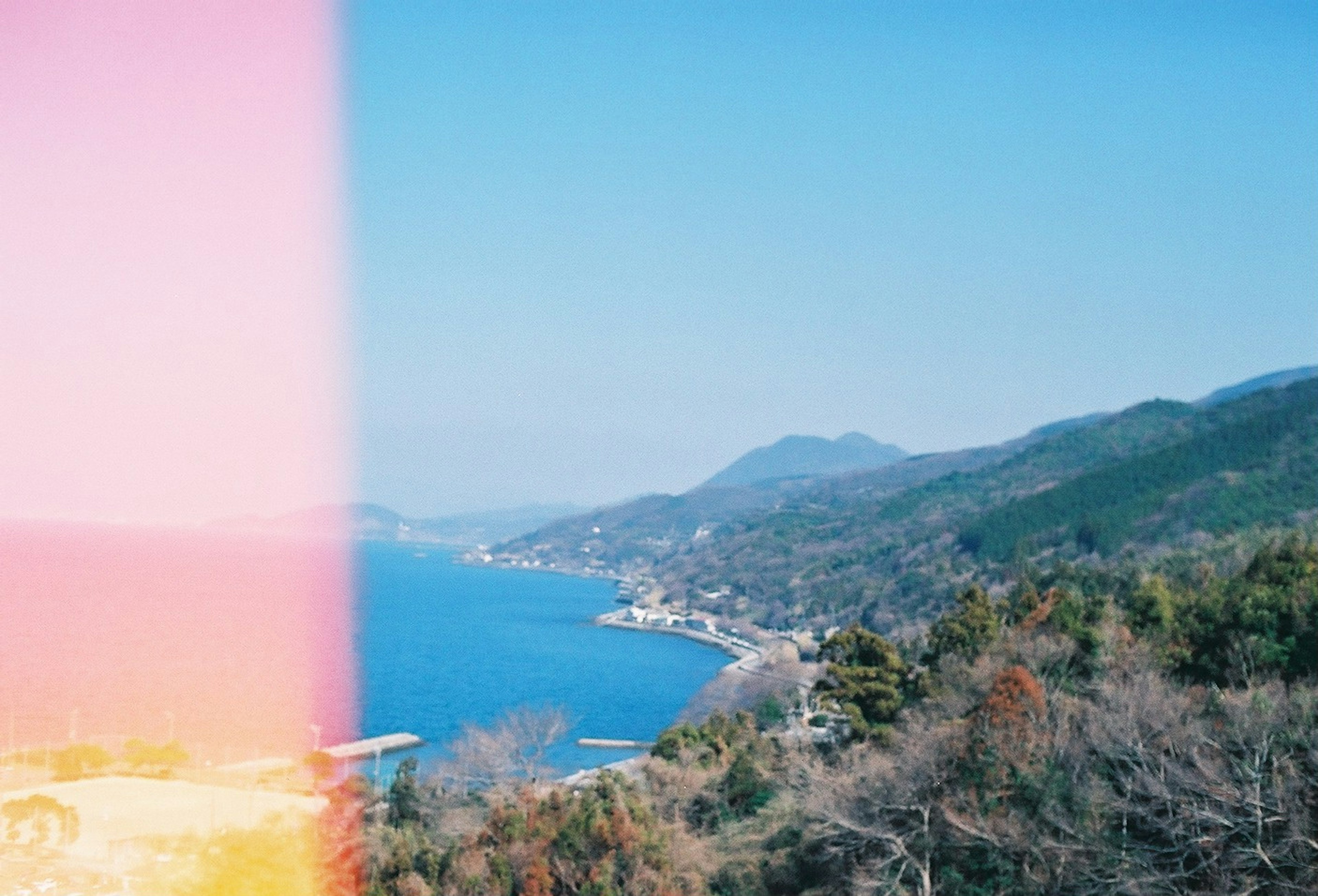 Vista panoramica dell'oceano blu e delle montagne con perdita di luce da pellicola