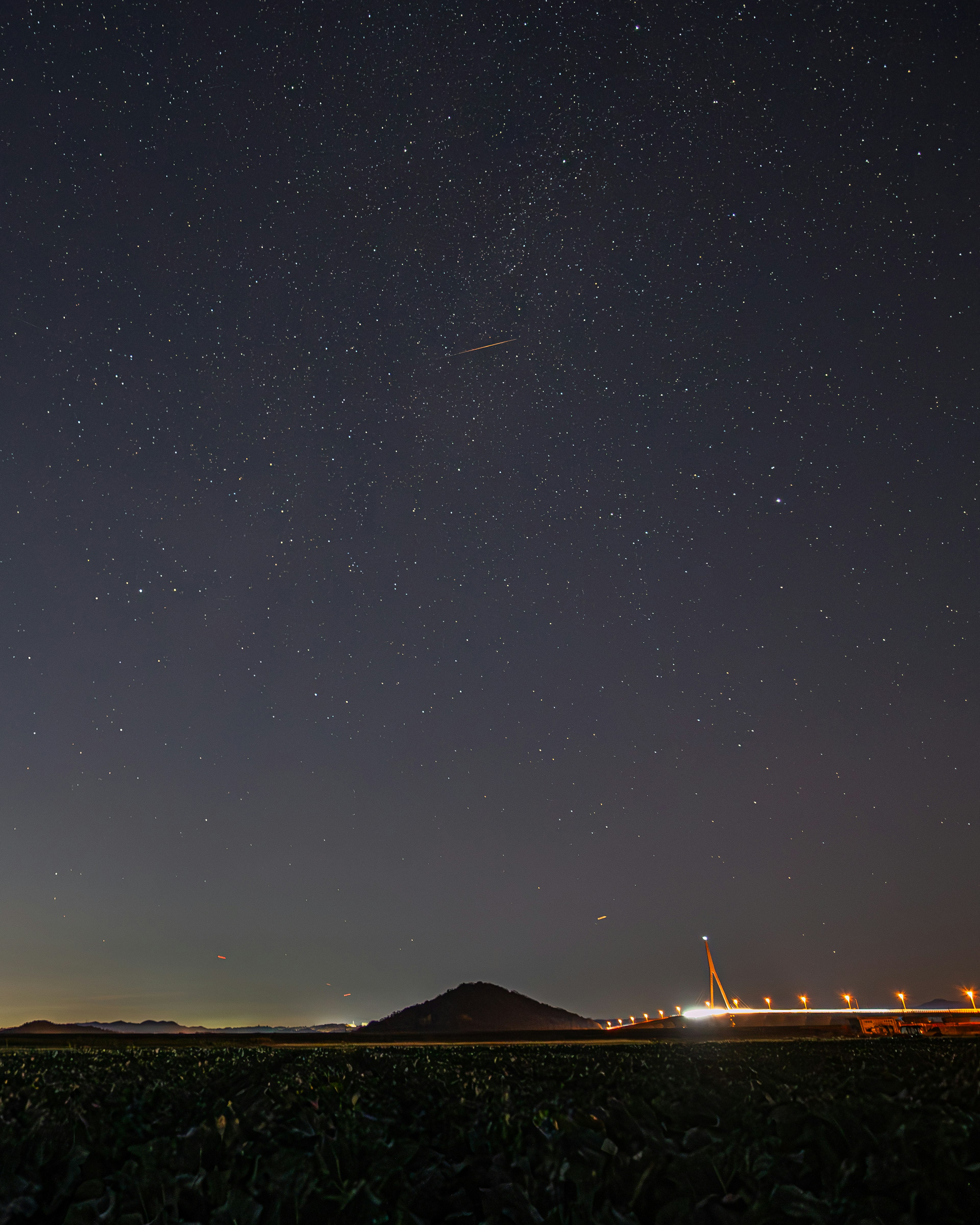 星空の下に広がる風景と橋の明かり