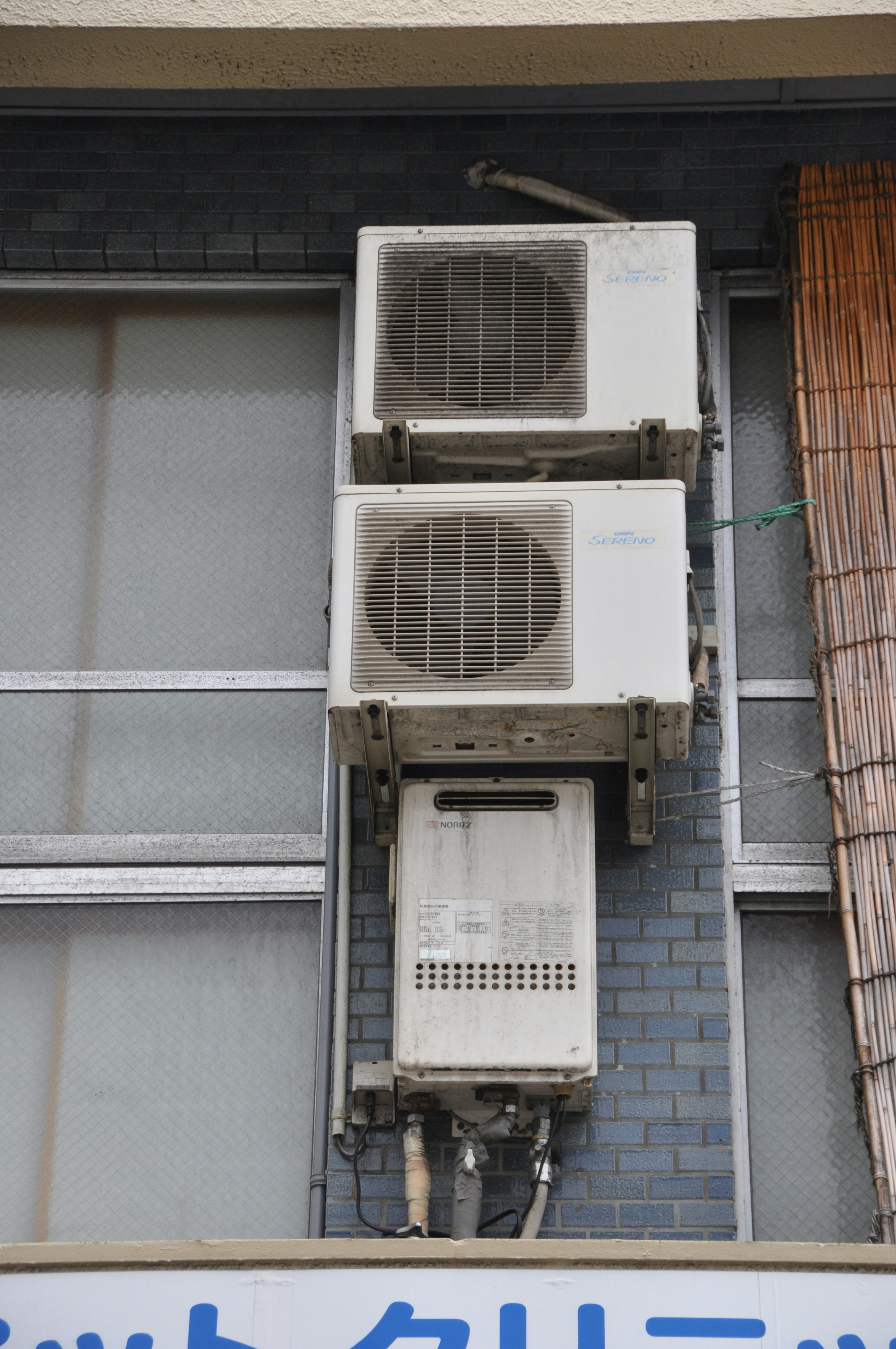 Image of two air conditioning units and one outdoor unit mounted on a building exterior