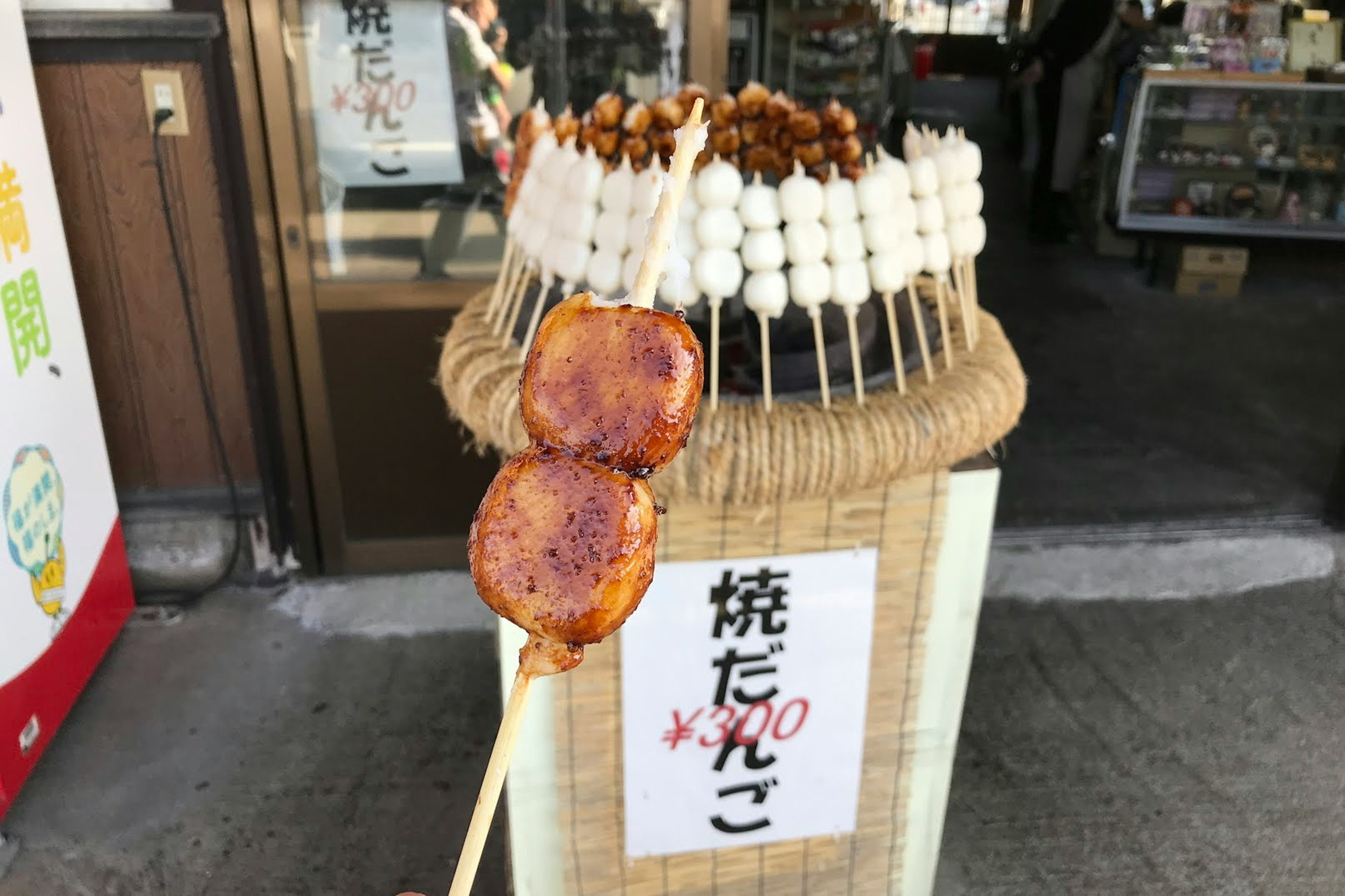 焼き団子の串が並ぶ屋台の前に焼き団子の串が持たれている