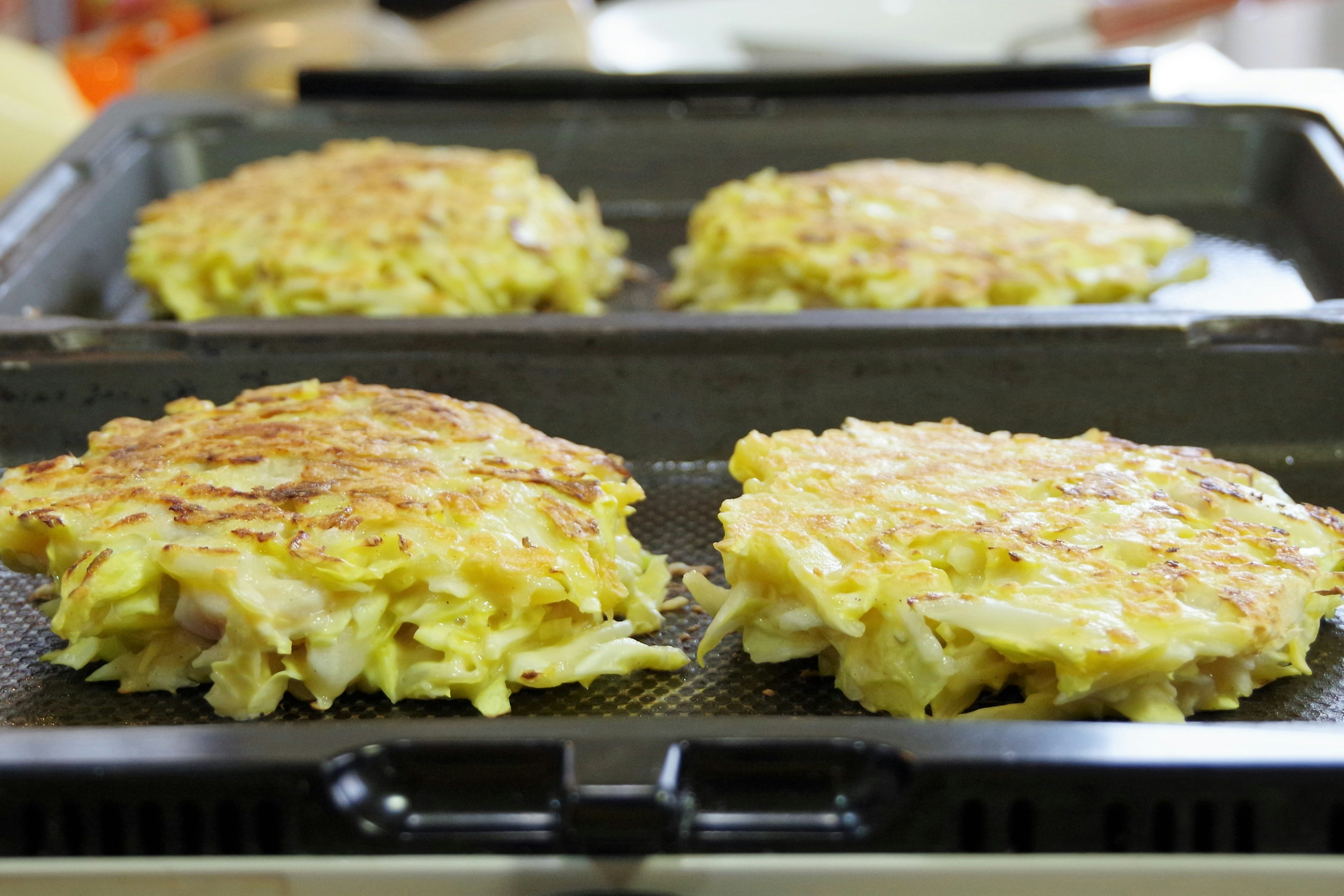 Four cabbage pancakes cooking on a grill