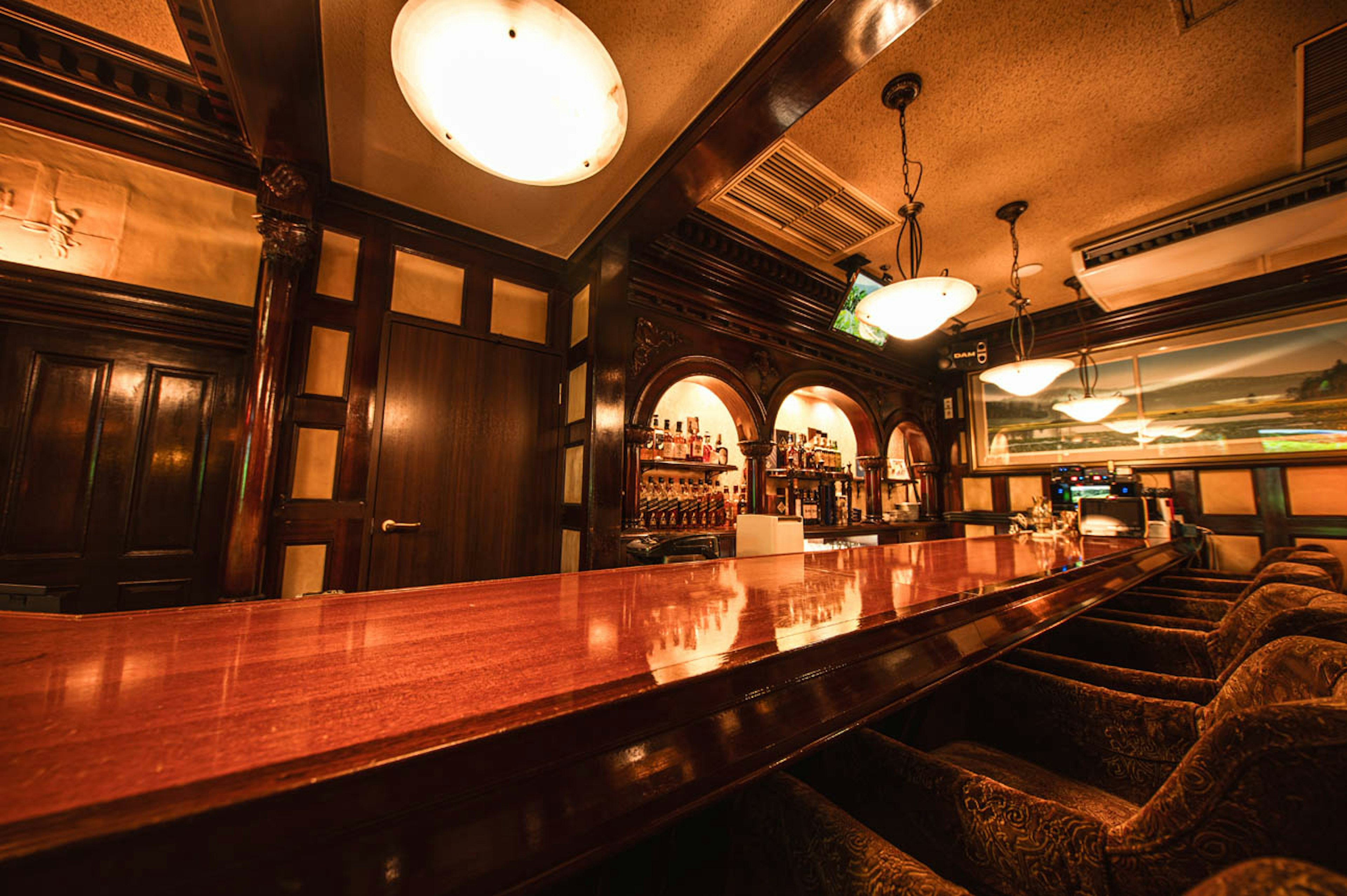 Interior of a cozy bar featuring a long wooden counter and warm lighting