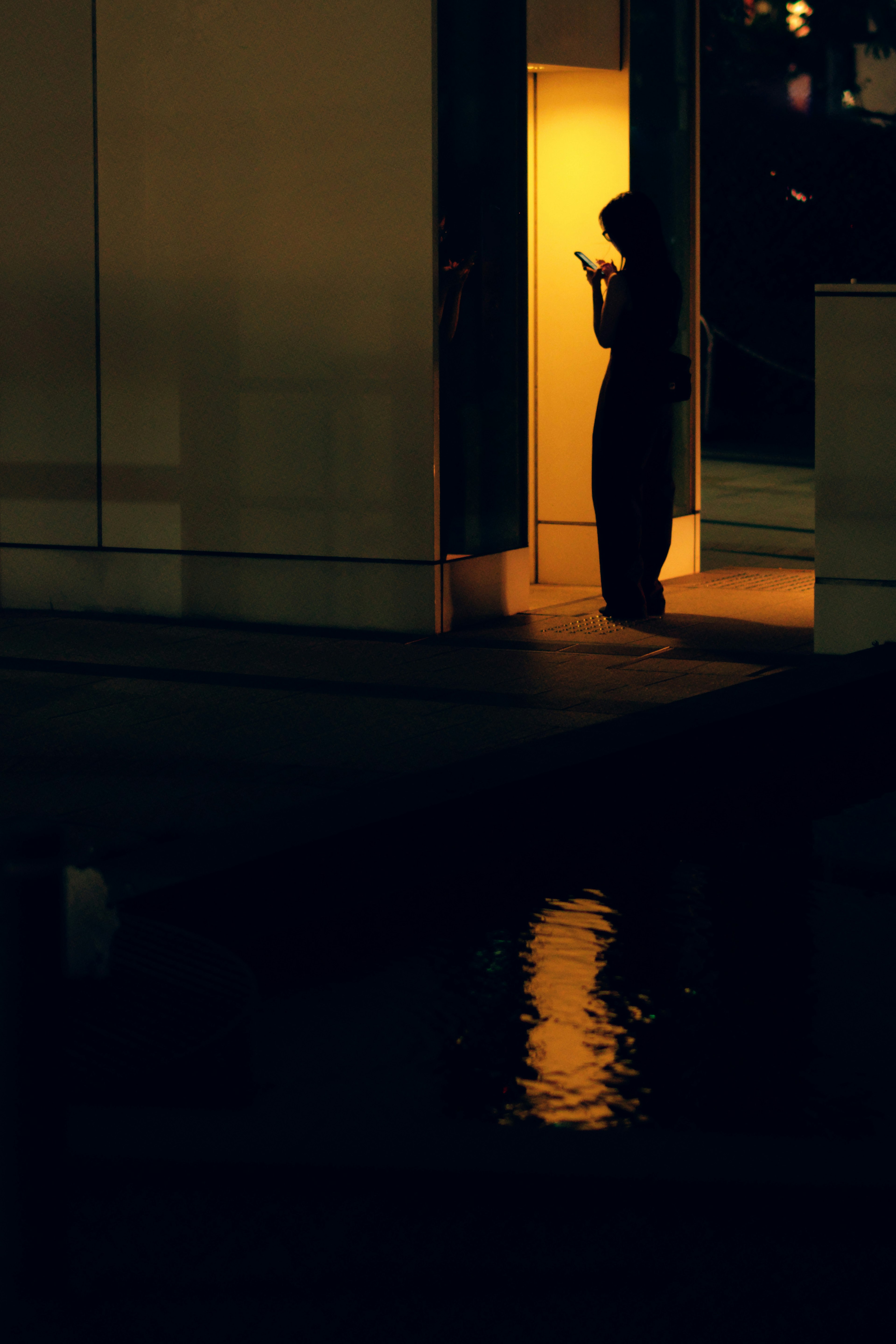 Silhouette of a person standing in darkness illuminated by a bright doorway