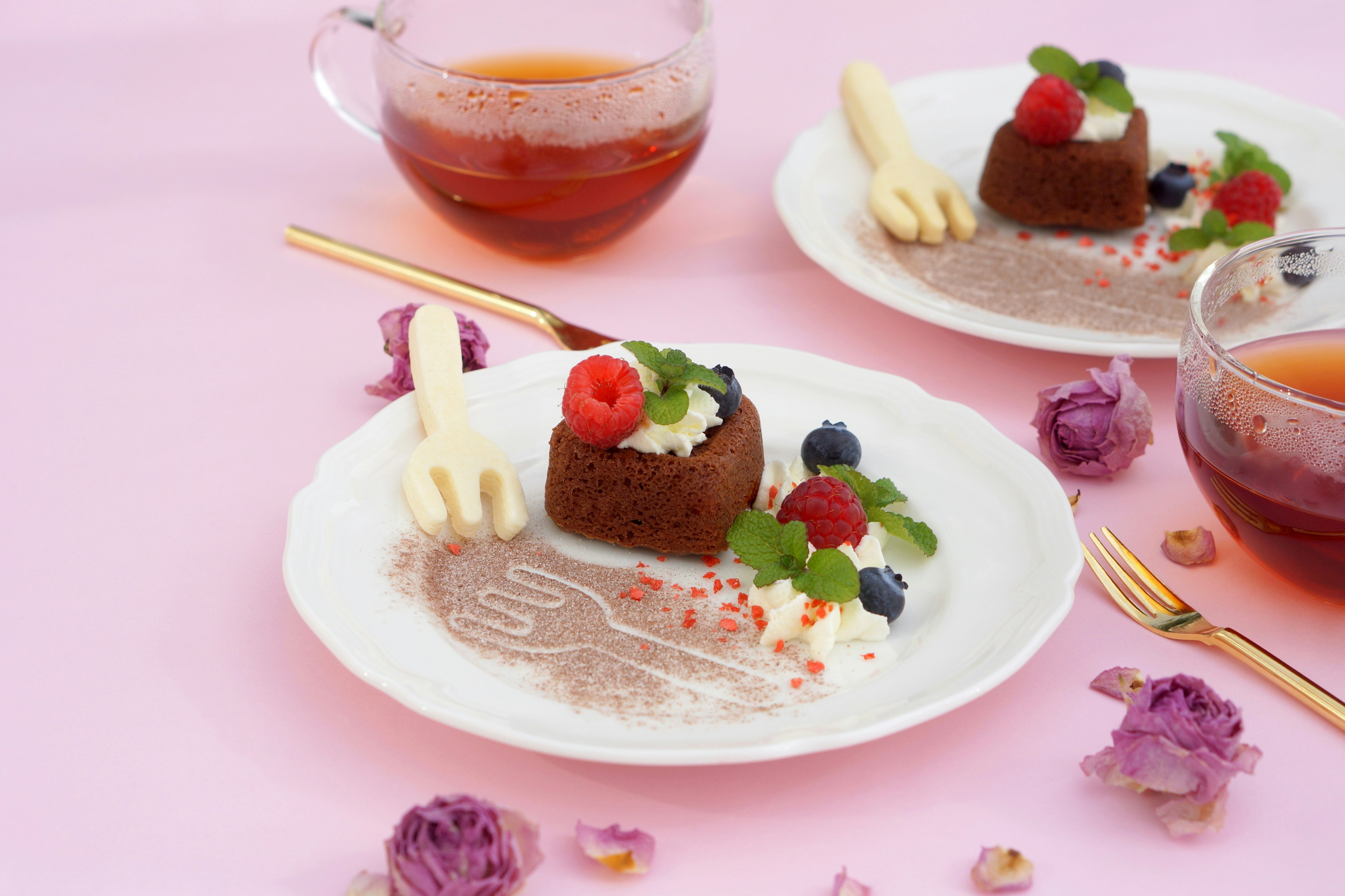 Piatto di dessert al cioccolato con frutti di bosco e menta su uno sfondo rosa