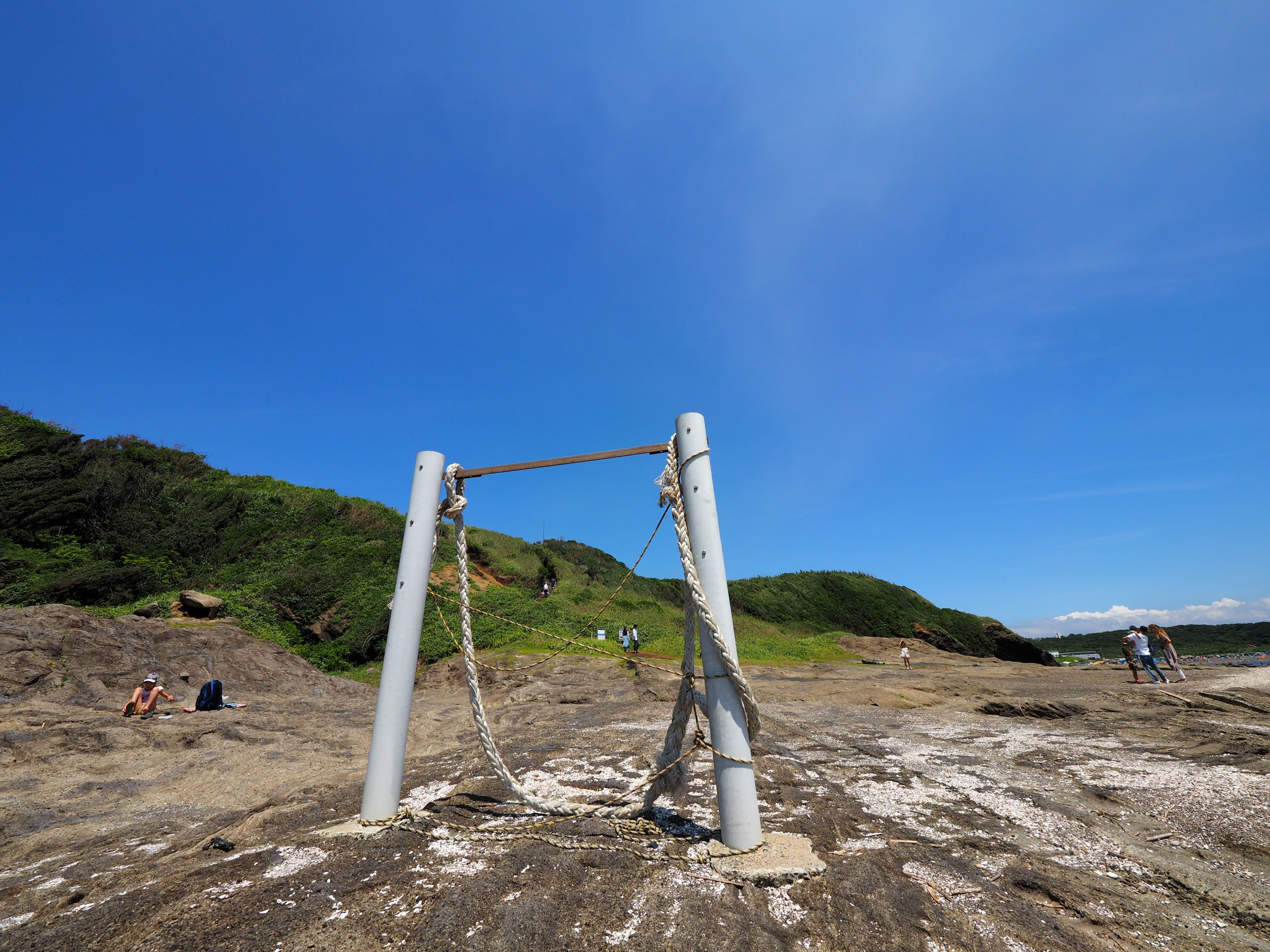 Swing frame under a blue sky with people in the background