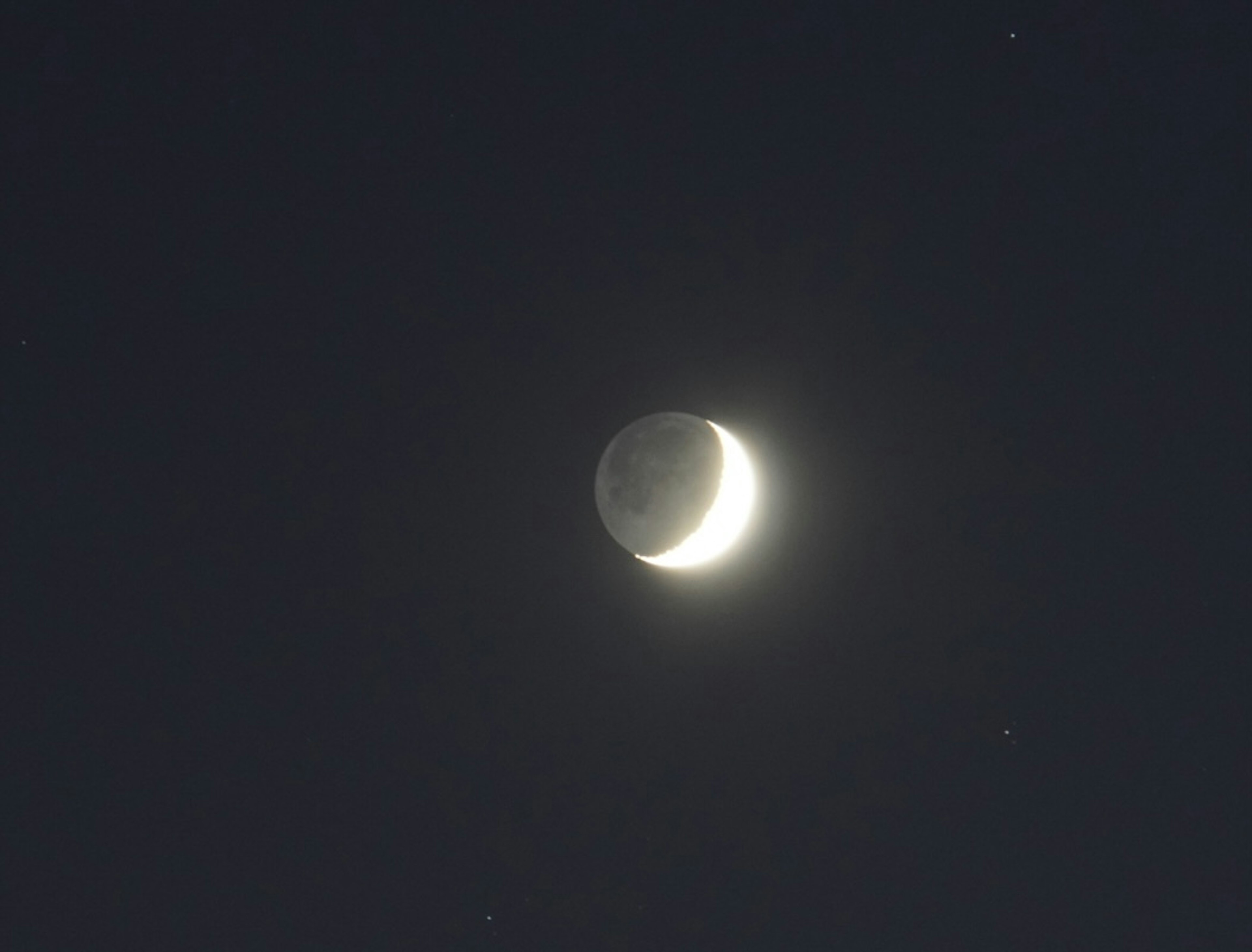 Bulan sabit tipis di langit malam dengan bintang-bintang