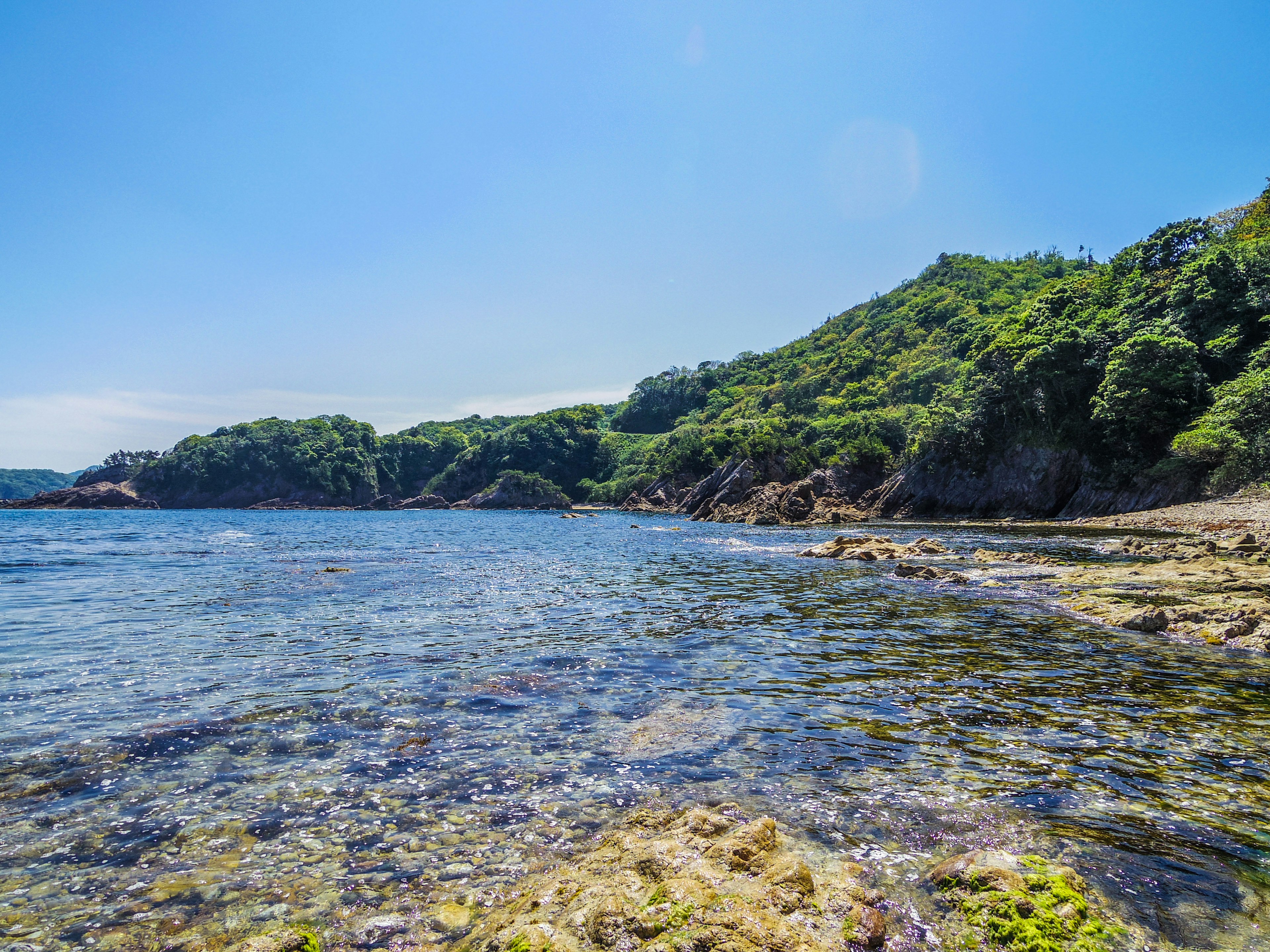 Landschaftsansicht mit blauem Meer und grünen Hügeln