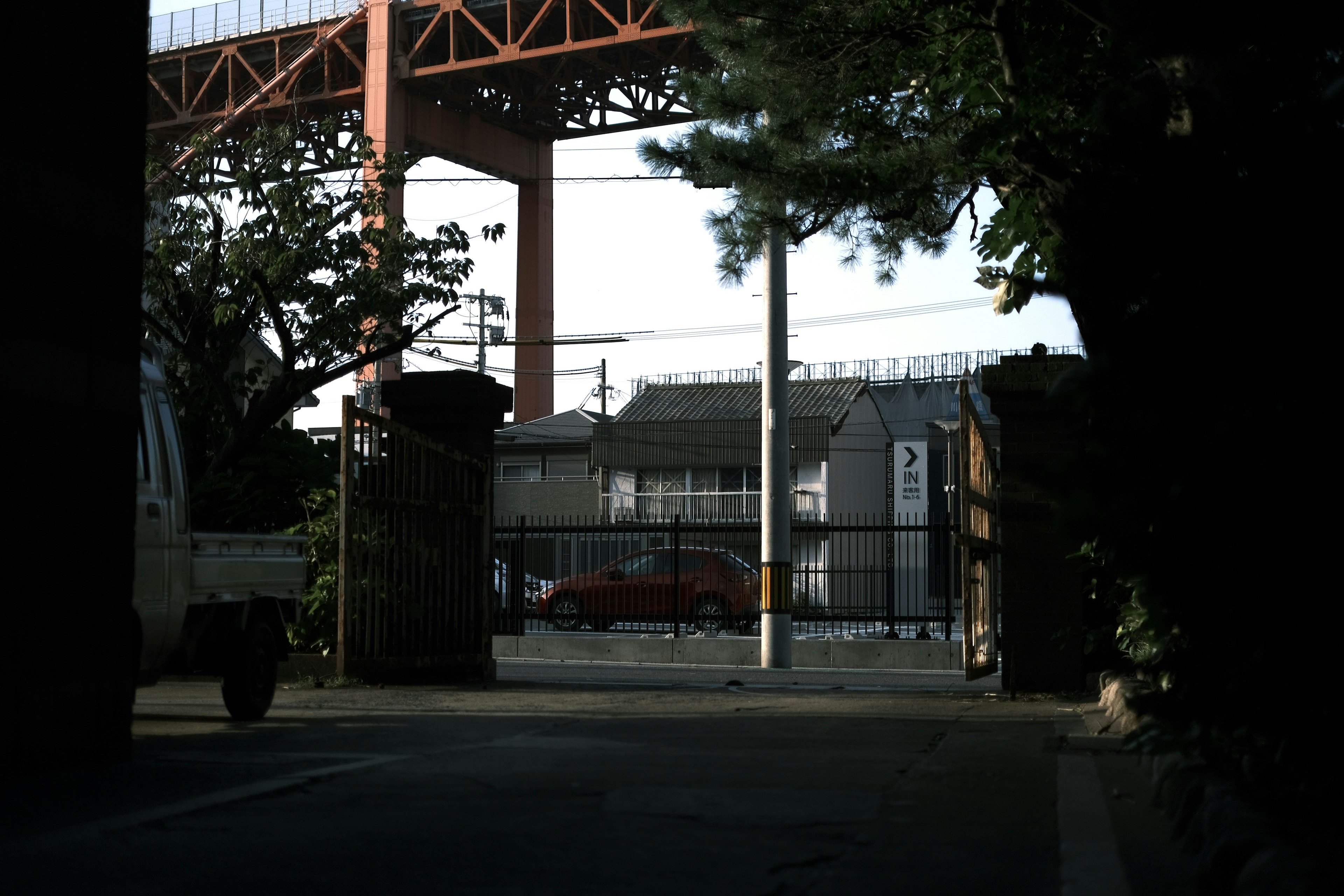 Vue d'un quartier résidentiel et d'une voiture rouge à travers une porte sous un pont ferroviaire