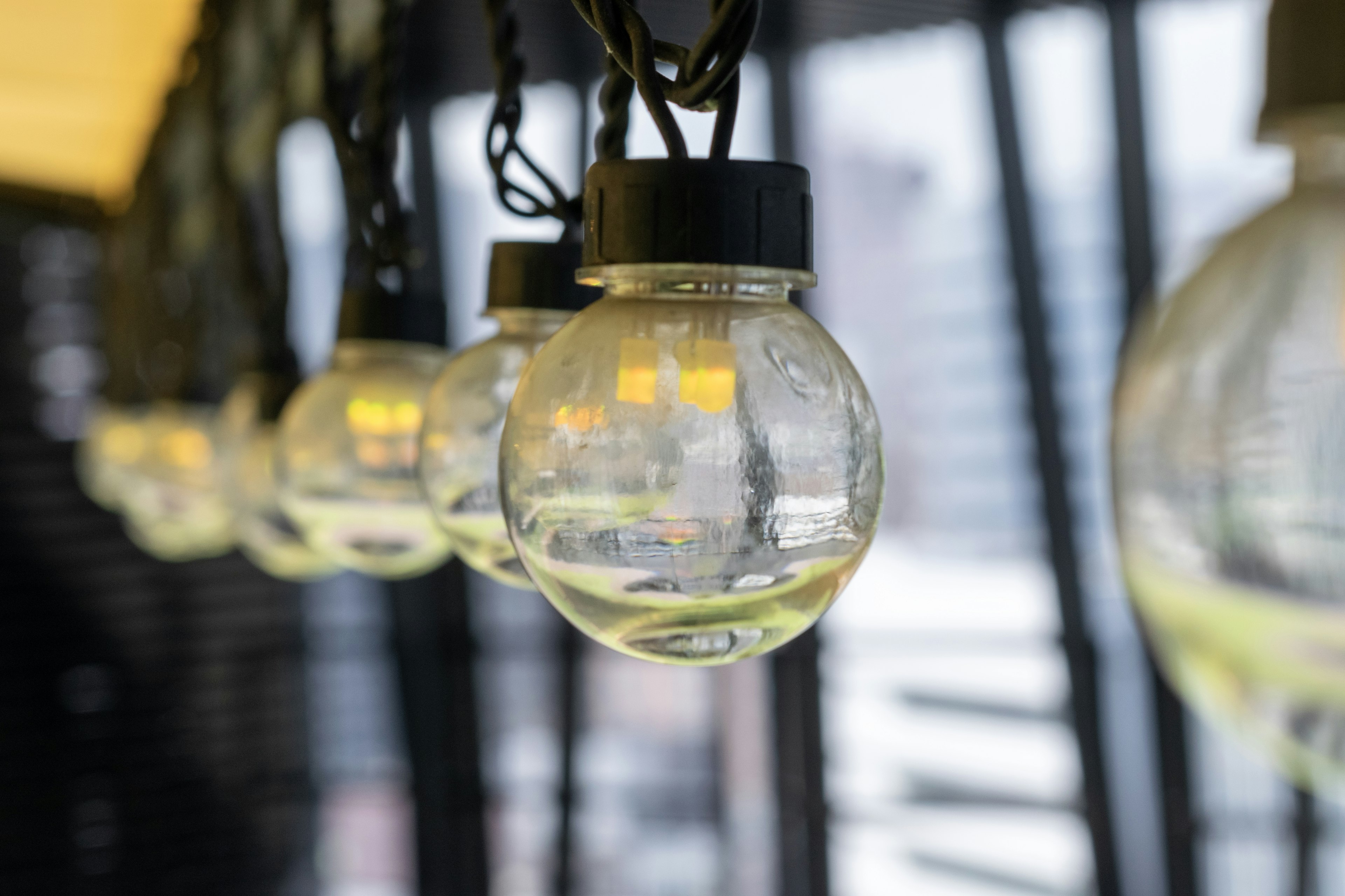 A row of glass spherical lamps illuminated against a blurred outdoor background