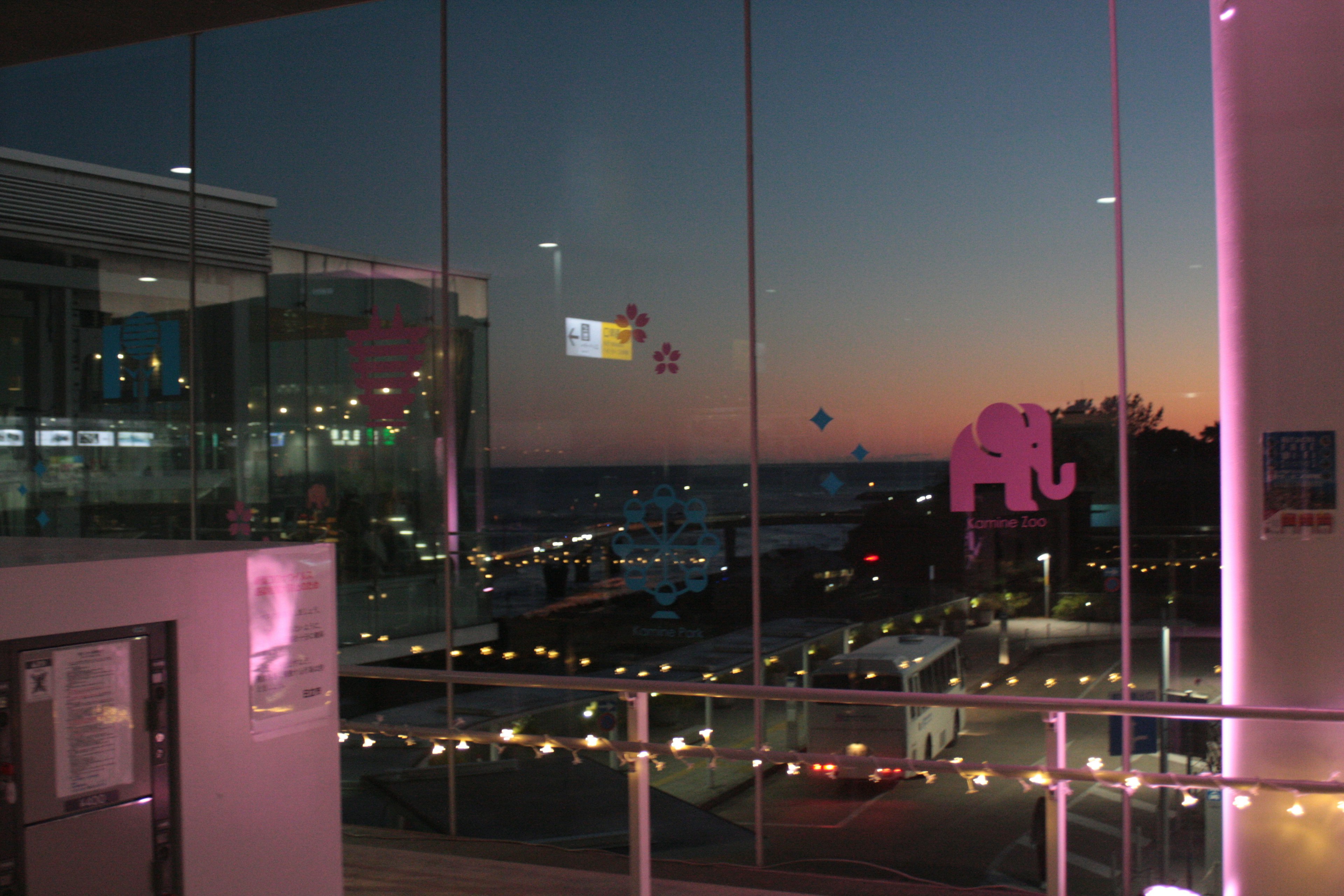 Glass window with pink elephant decoration overlooking the sea at sunset