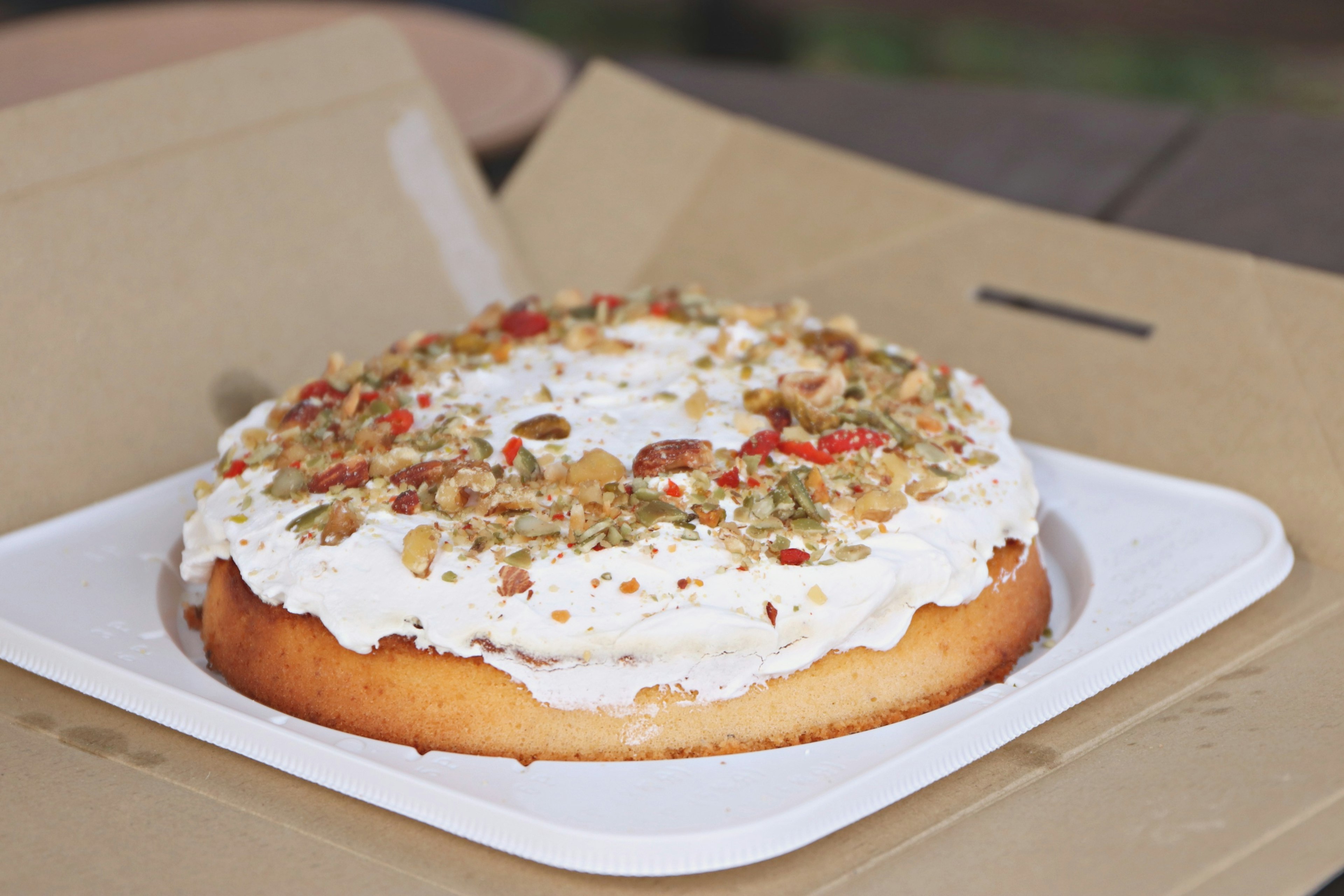 A cake topped with cream and nuts placed on a white plate