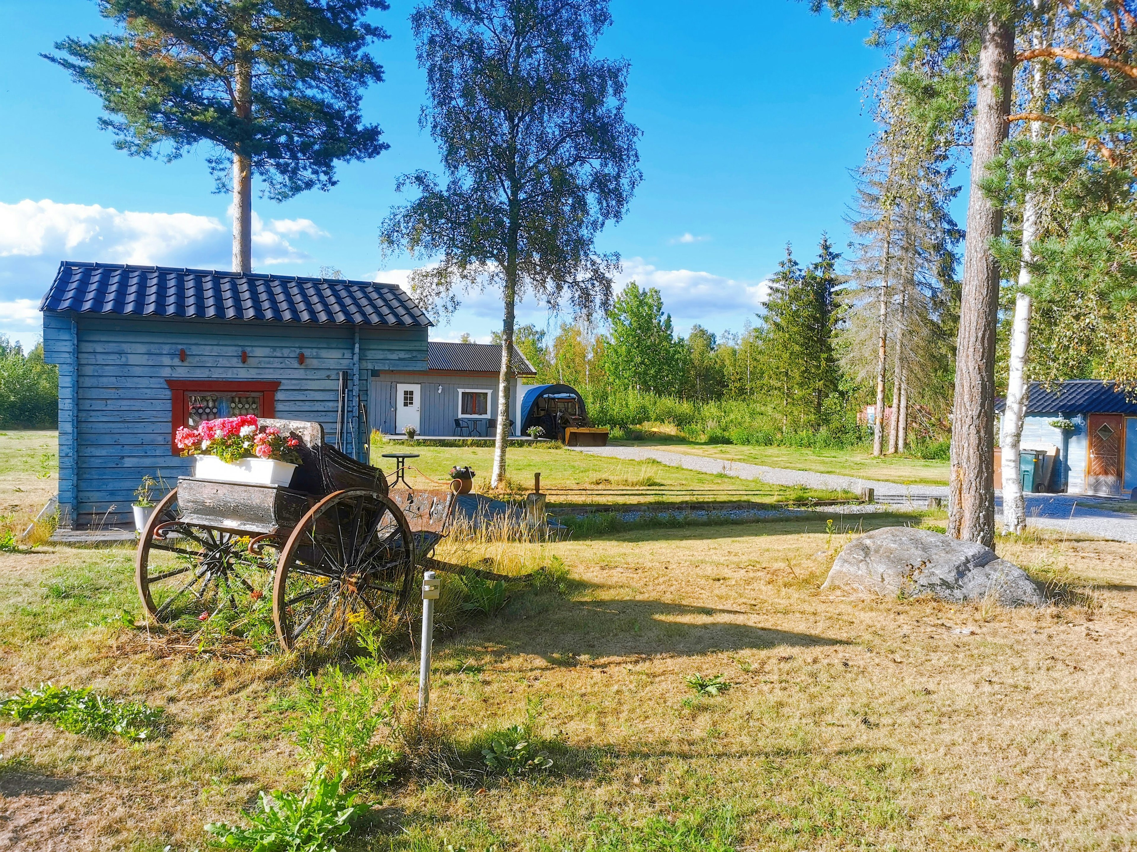 Landscape featuring a blue shed and an old cart under a clear sky