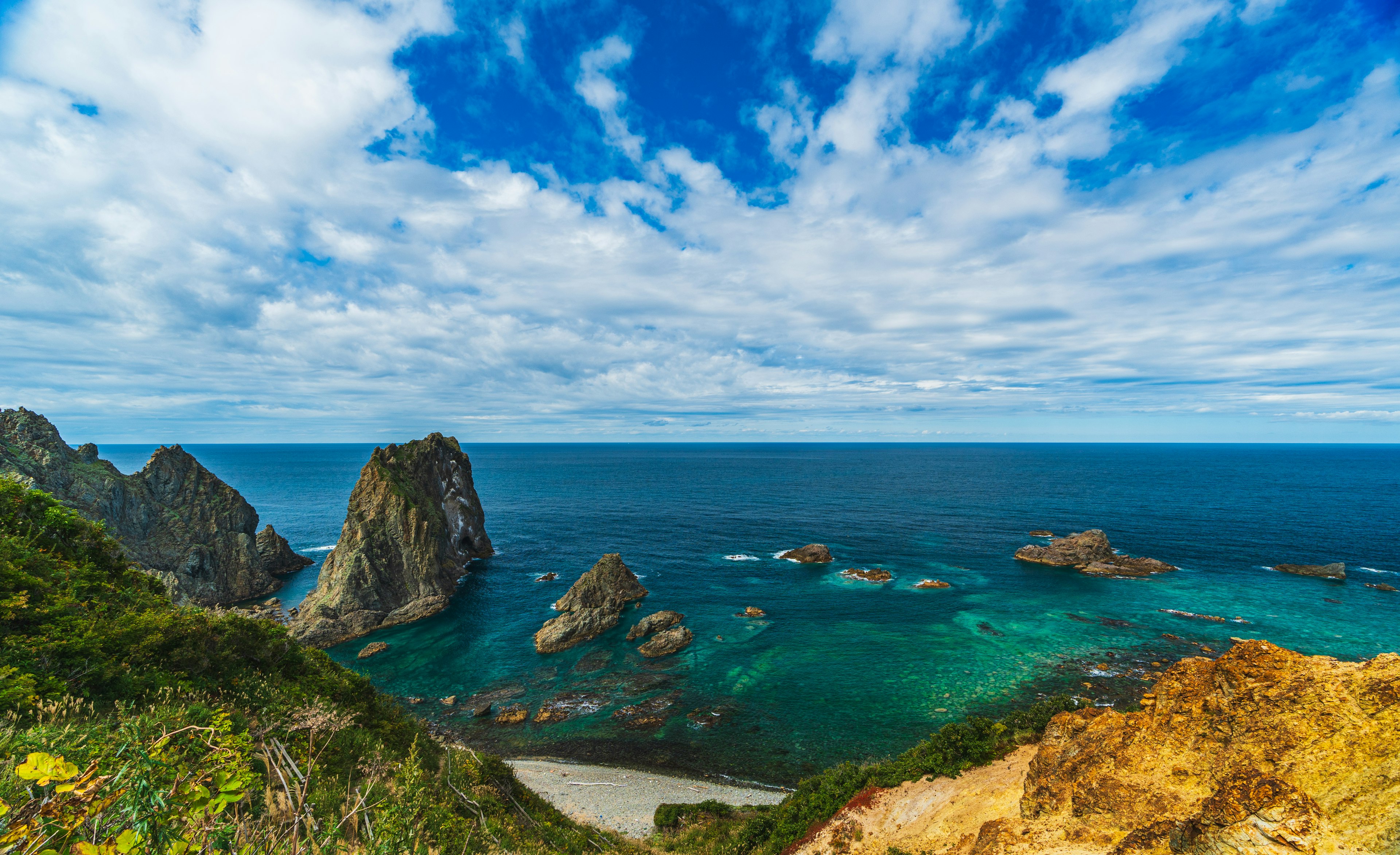 美しい海と岩の風景、青い空と白い雲が広がる