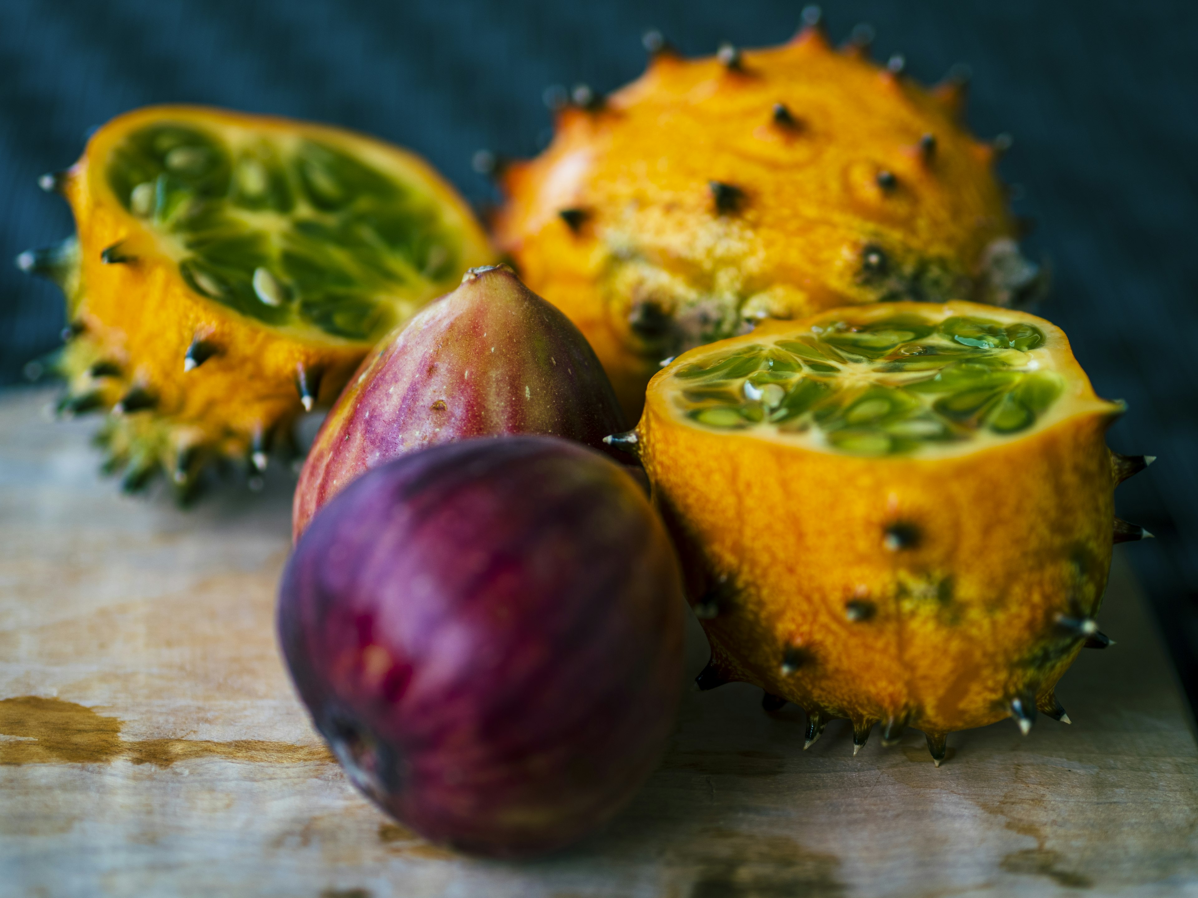 Fruta espinosa amarilla y higo morado sobre una tabla de madera