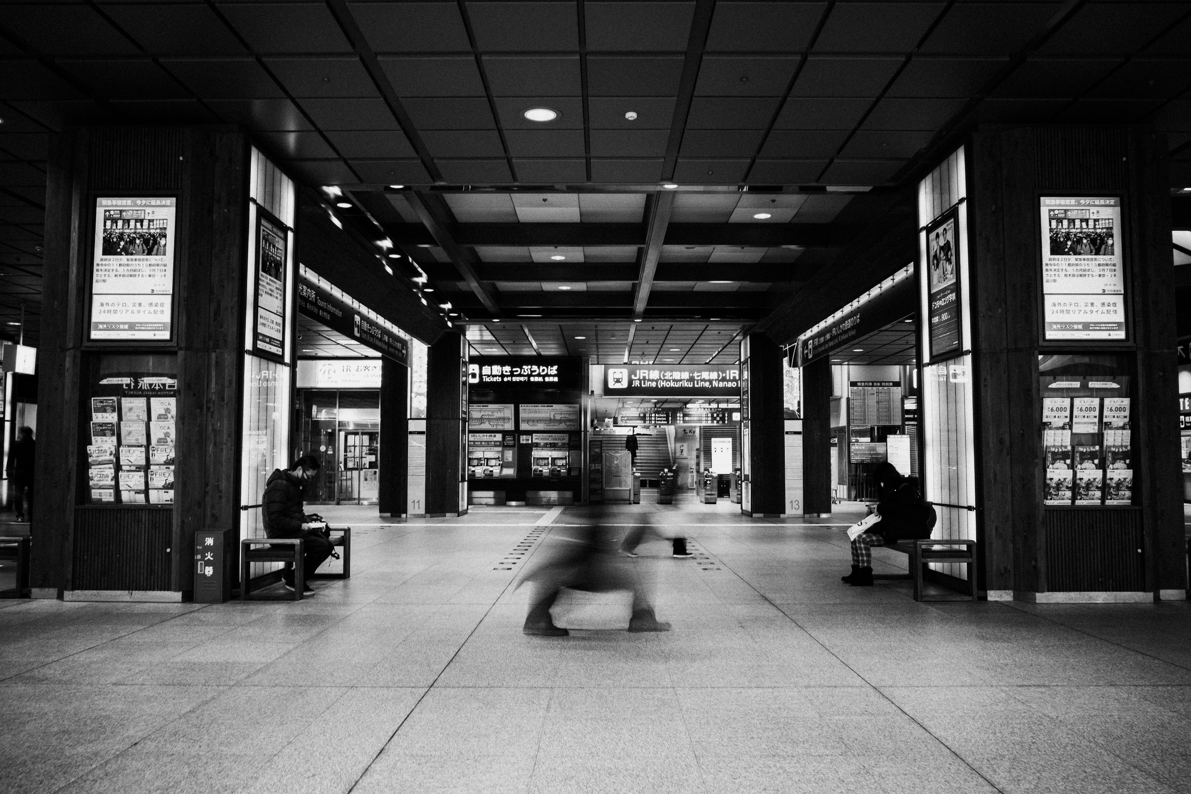 Black and white interior of a train station with moving people