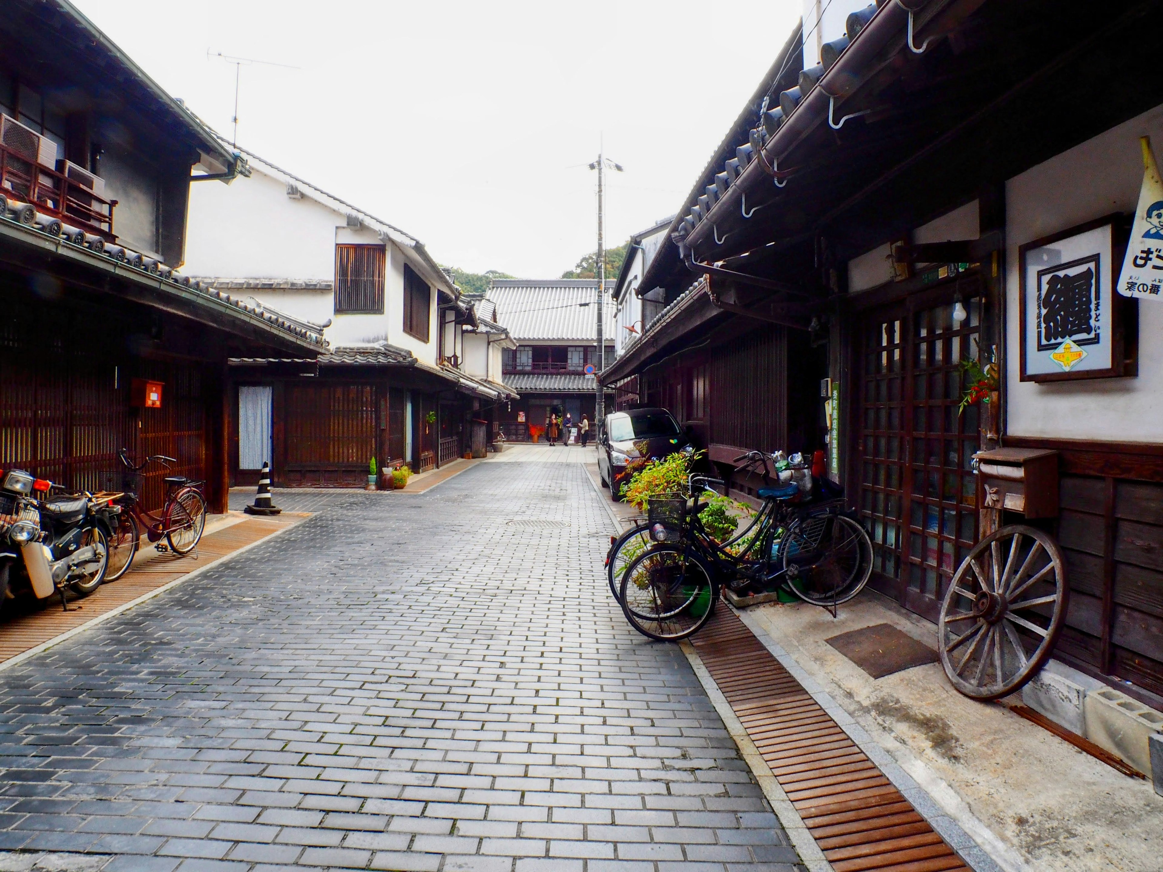 Quiet street in a traditional Japanese town featuring bicycles and motorcycles