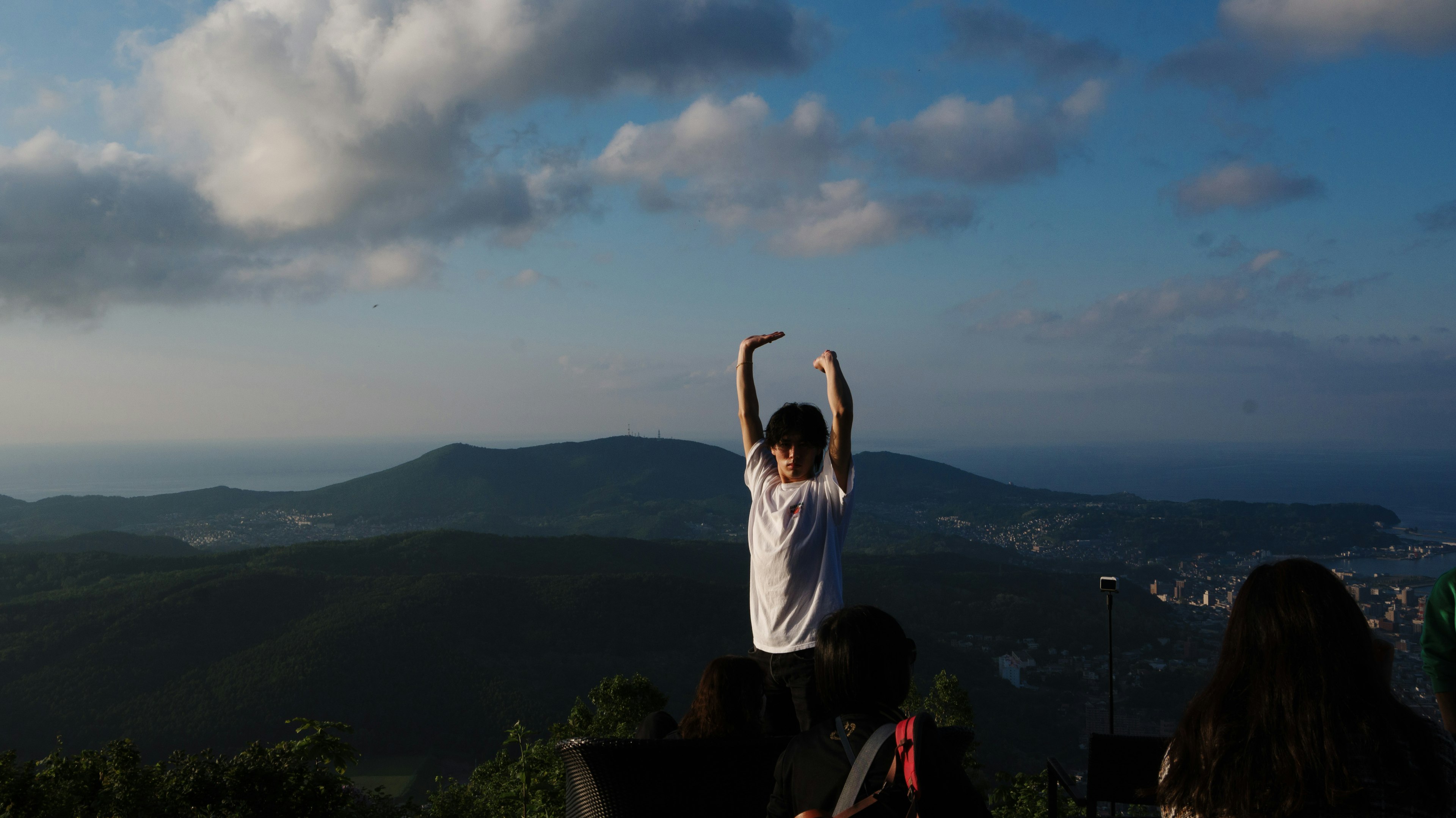 Une personne prenant une pose avec les bras levés devant un paysage de montagne