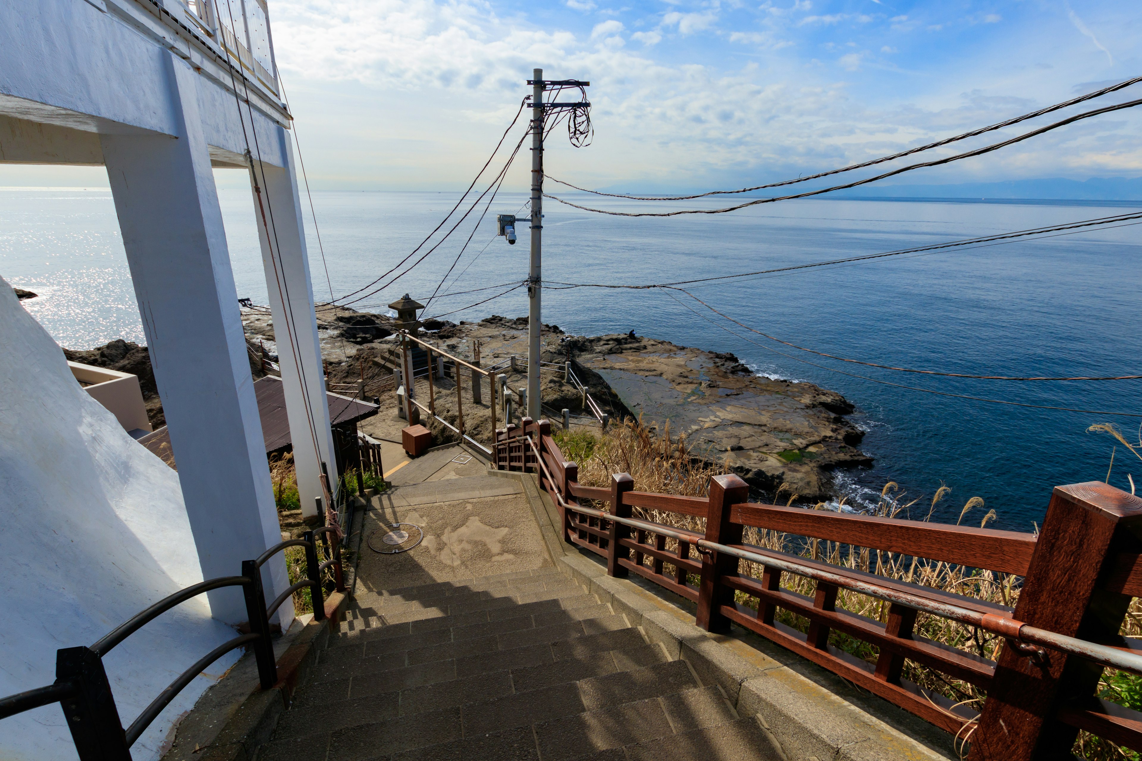 Escaliers menant à la mer avec vue sur des lignes électriques