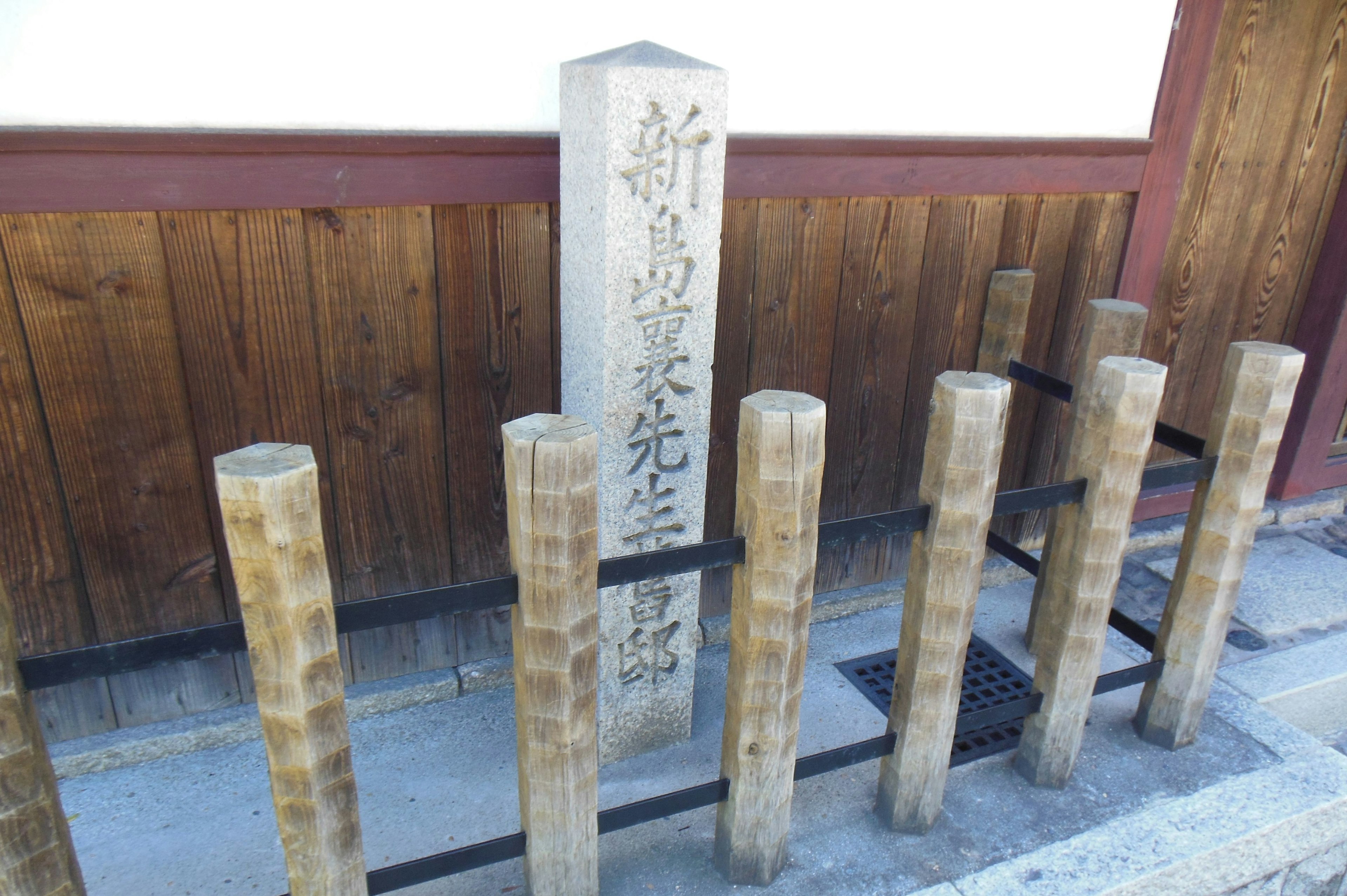 Foreground of a traditional building featuring a stone monument and wooden posts