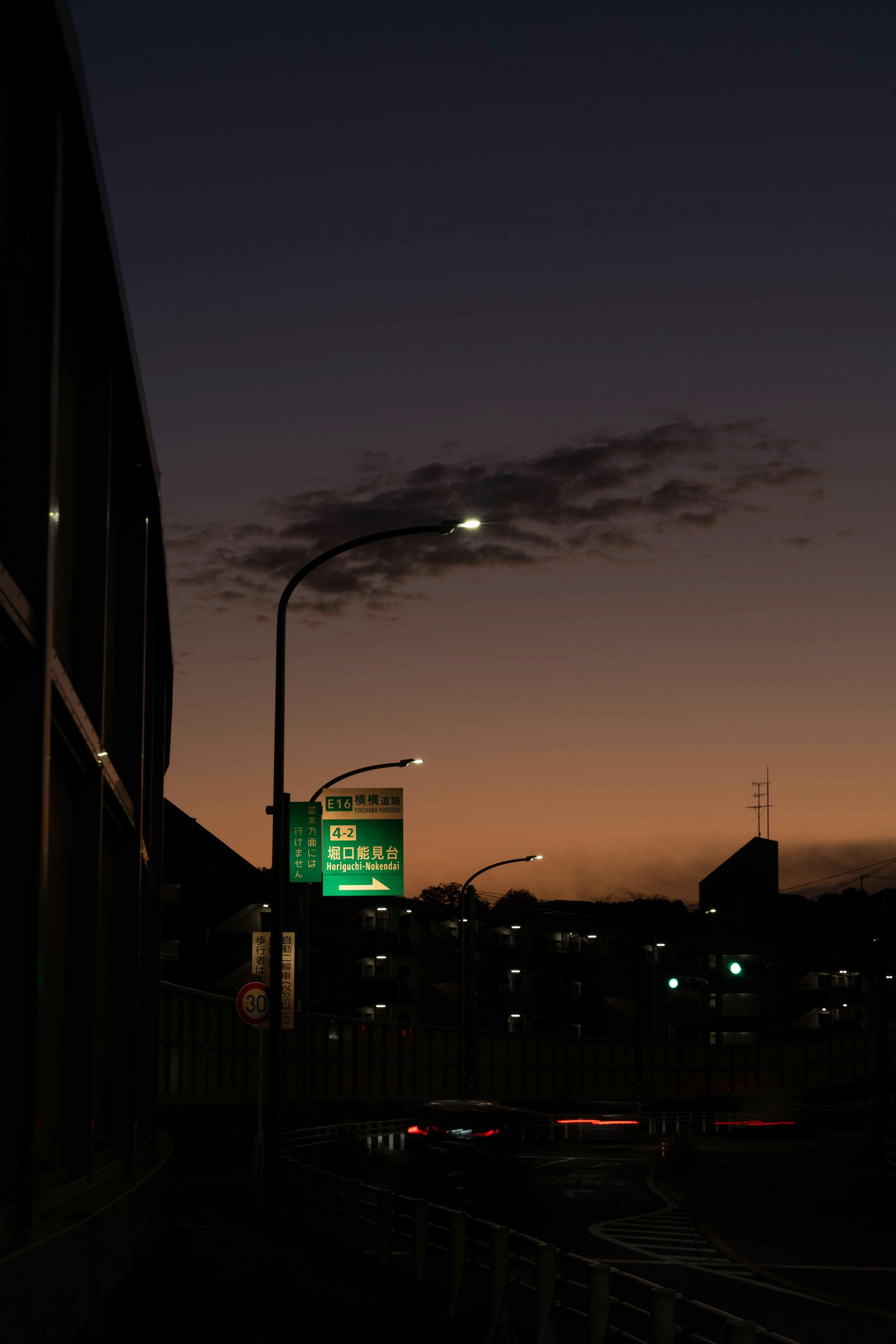 Pemandangan kota saat senja dengan lampu jalan dan papan nama