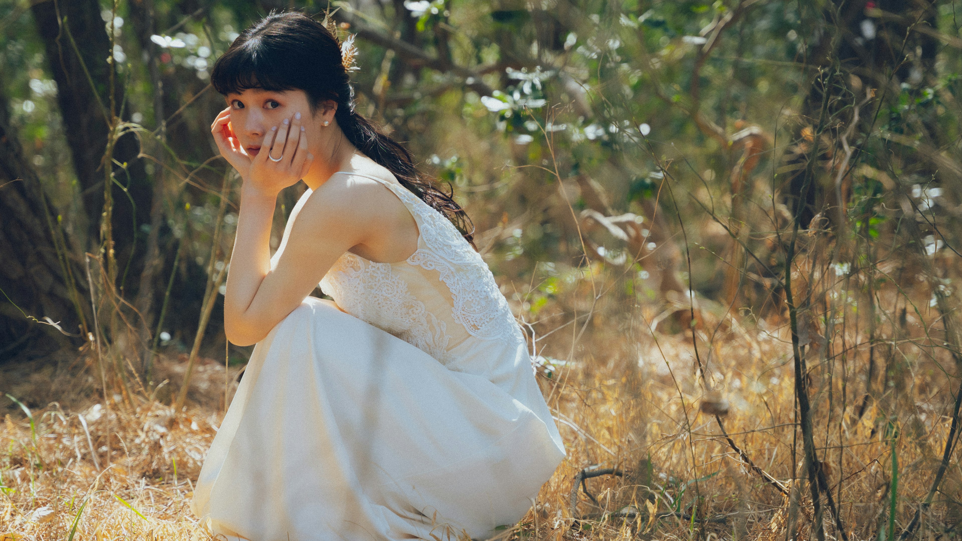 Una mujer con un vestido blanco sentada en un entorno forestal