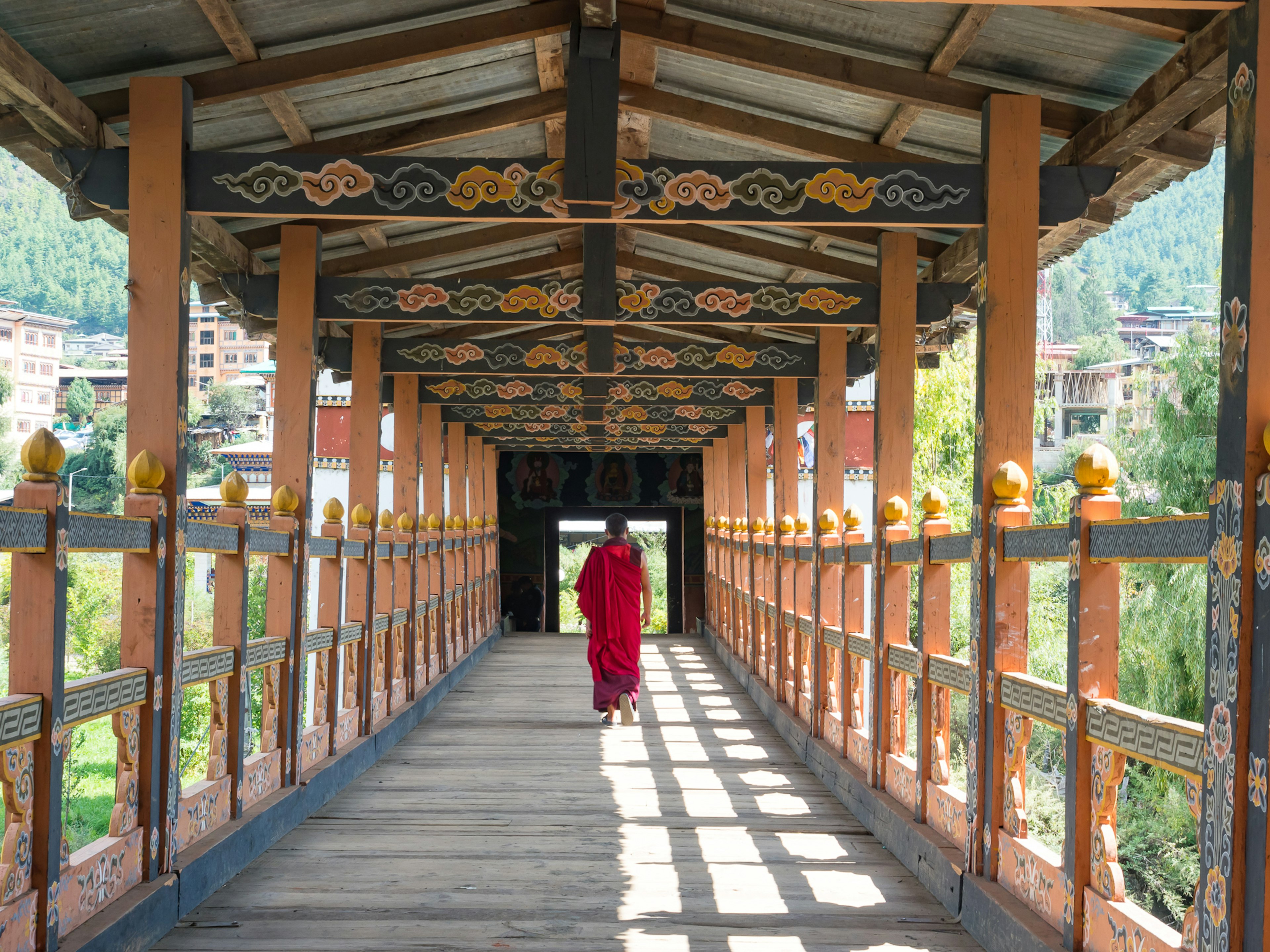 Monje caminando sobre un puente tradicional adornado con decoraciones intrincadas