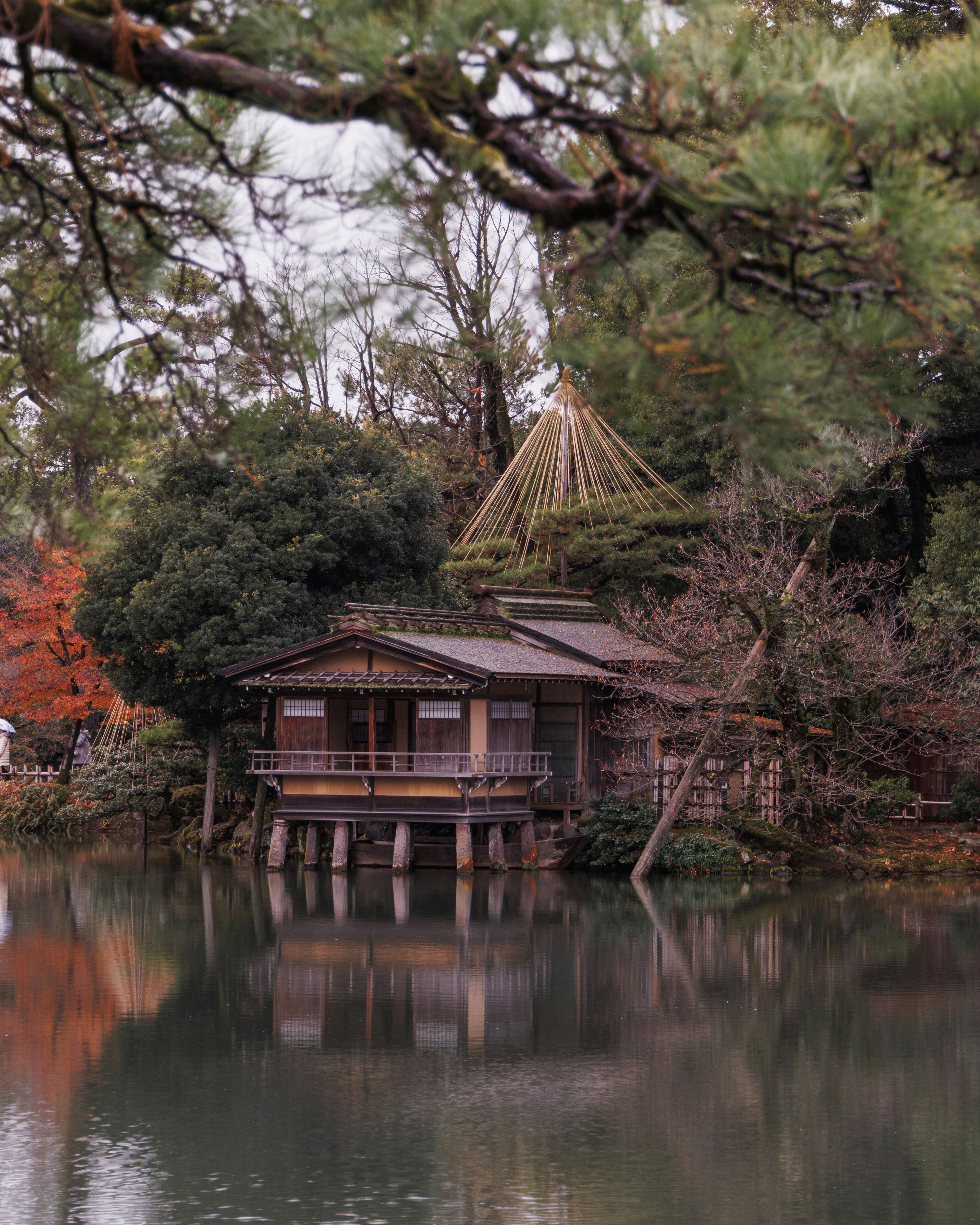 Traditional Japanese house by a tranquil pond surrounded by trees