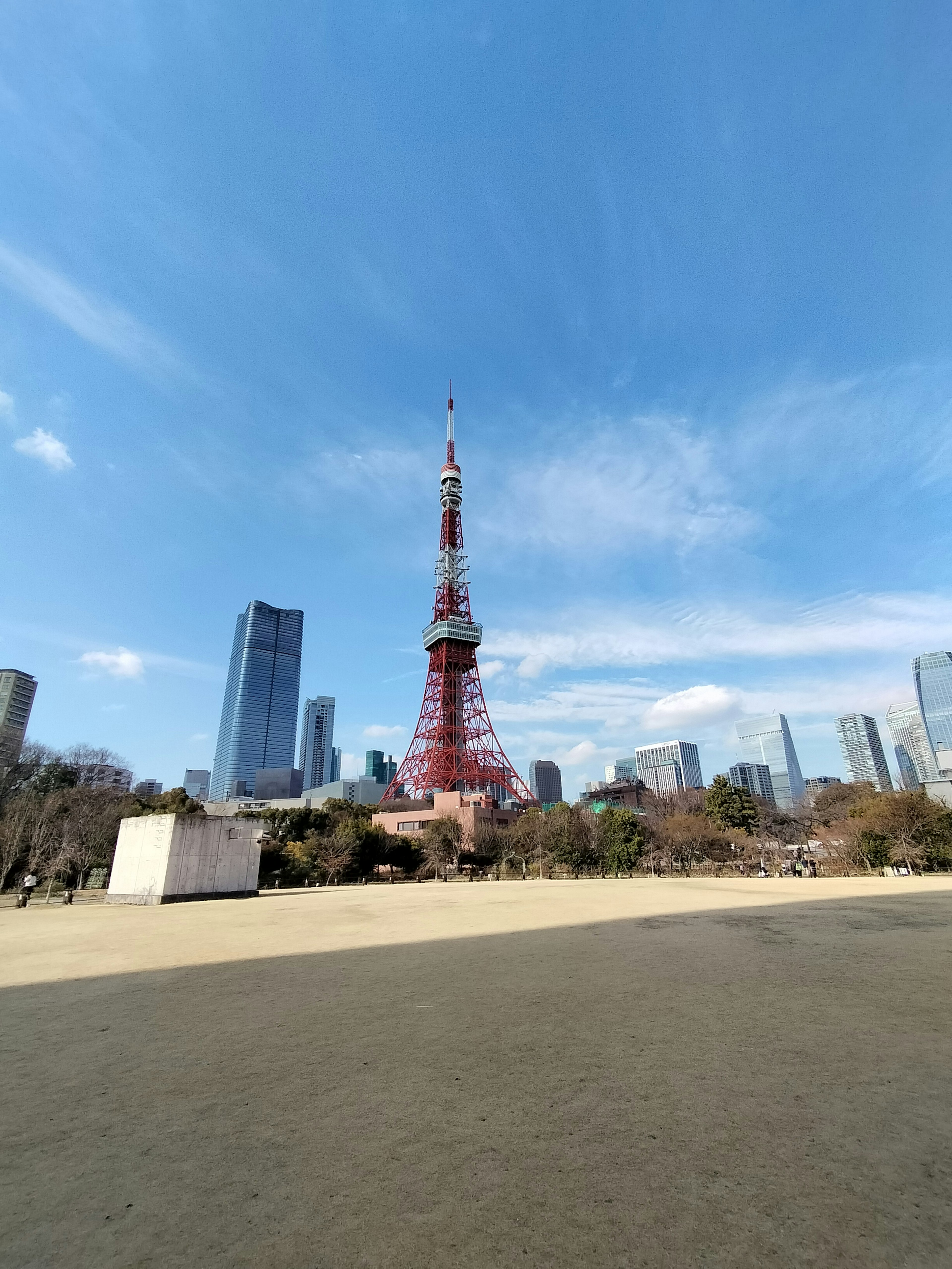 Tokyo Tower with surrounding skyscrapers under a clear blue sky