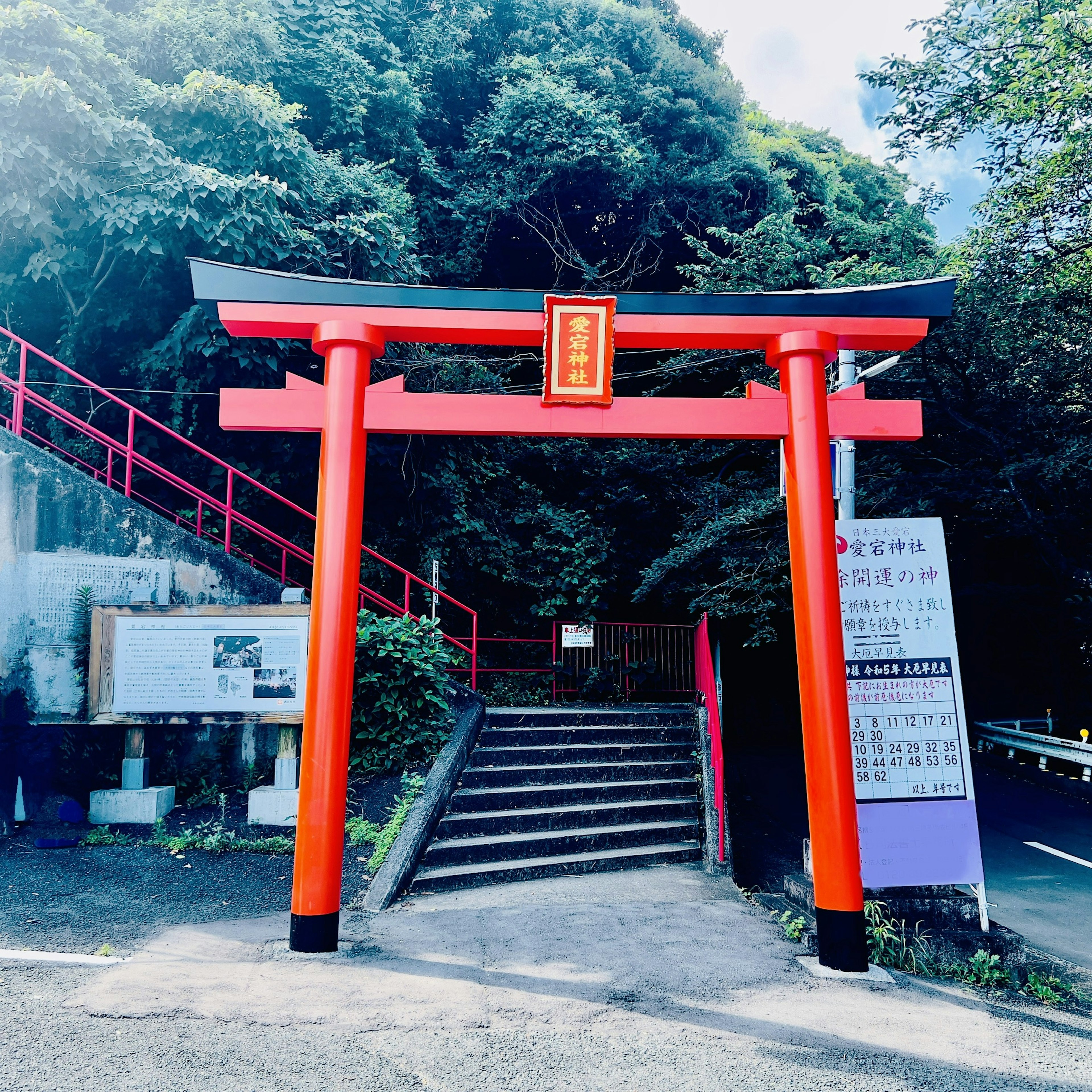 Gerbang torii merah dengan tangga dikelilingi oleh pepohonan rimbun