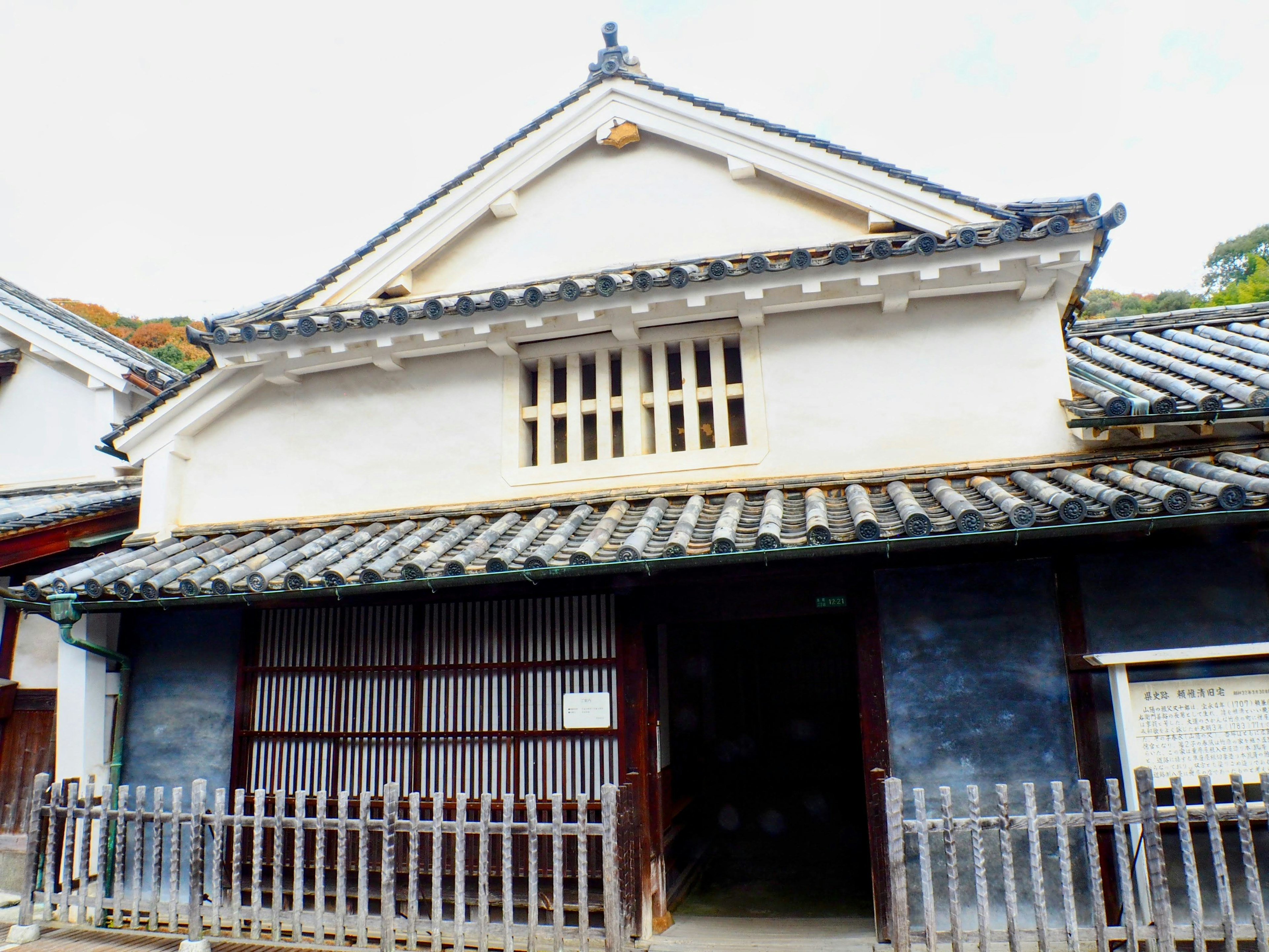 Exterior de un edificio japonés tradicional con paredes blancas y techo negro con entrada de rejilla