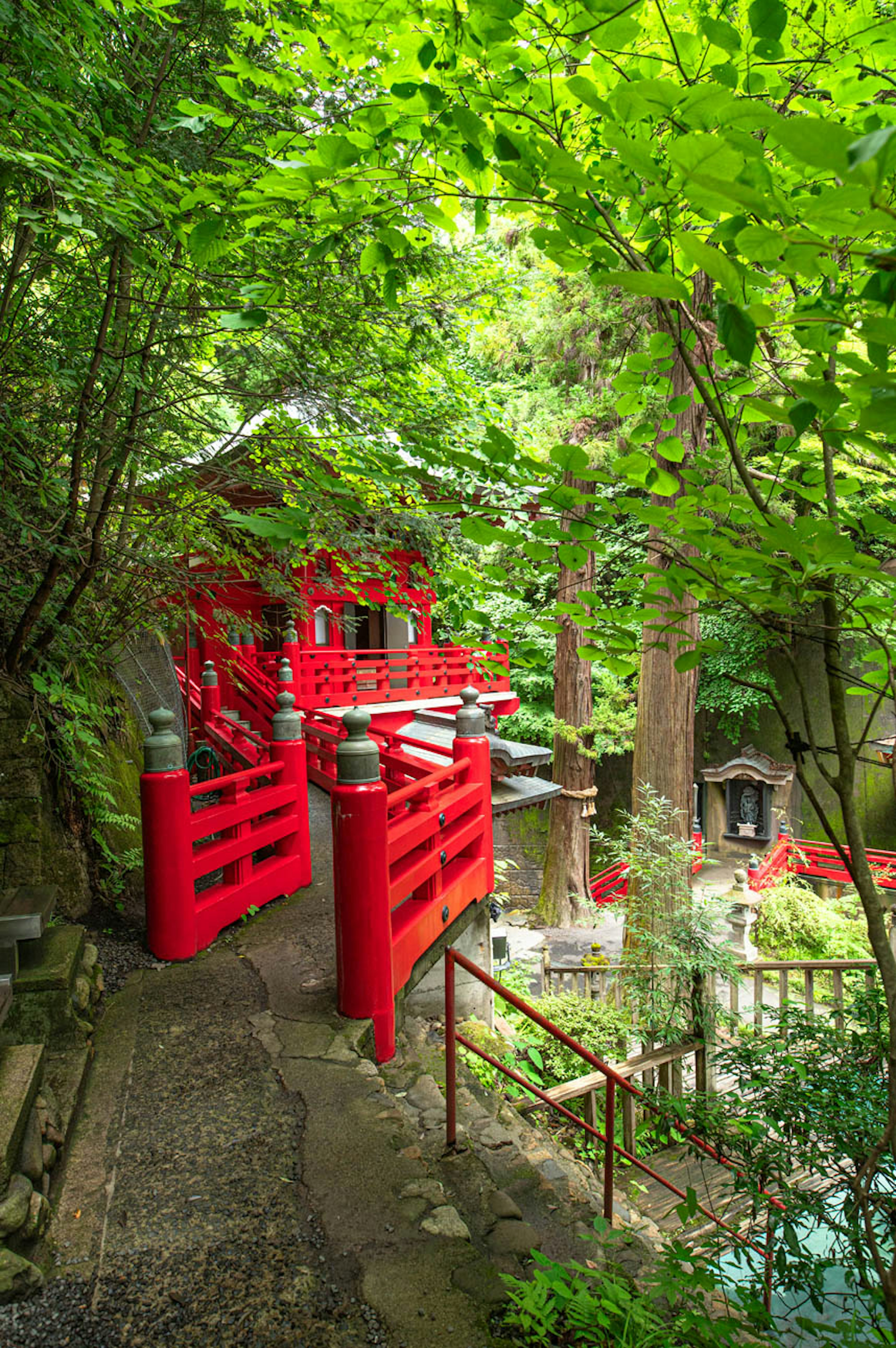 緑に囲まれた赤い橋と石の小道の風景