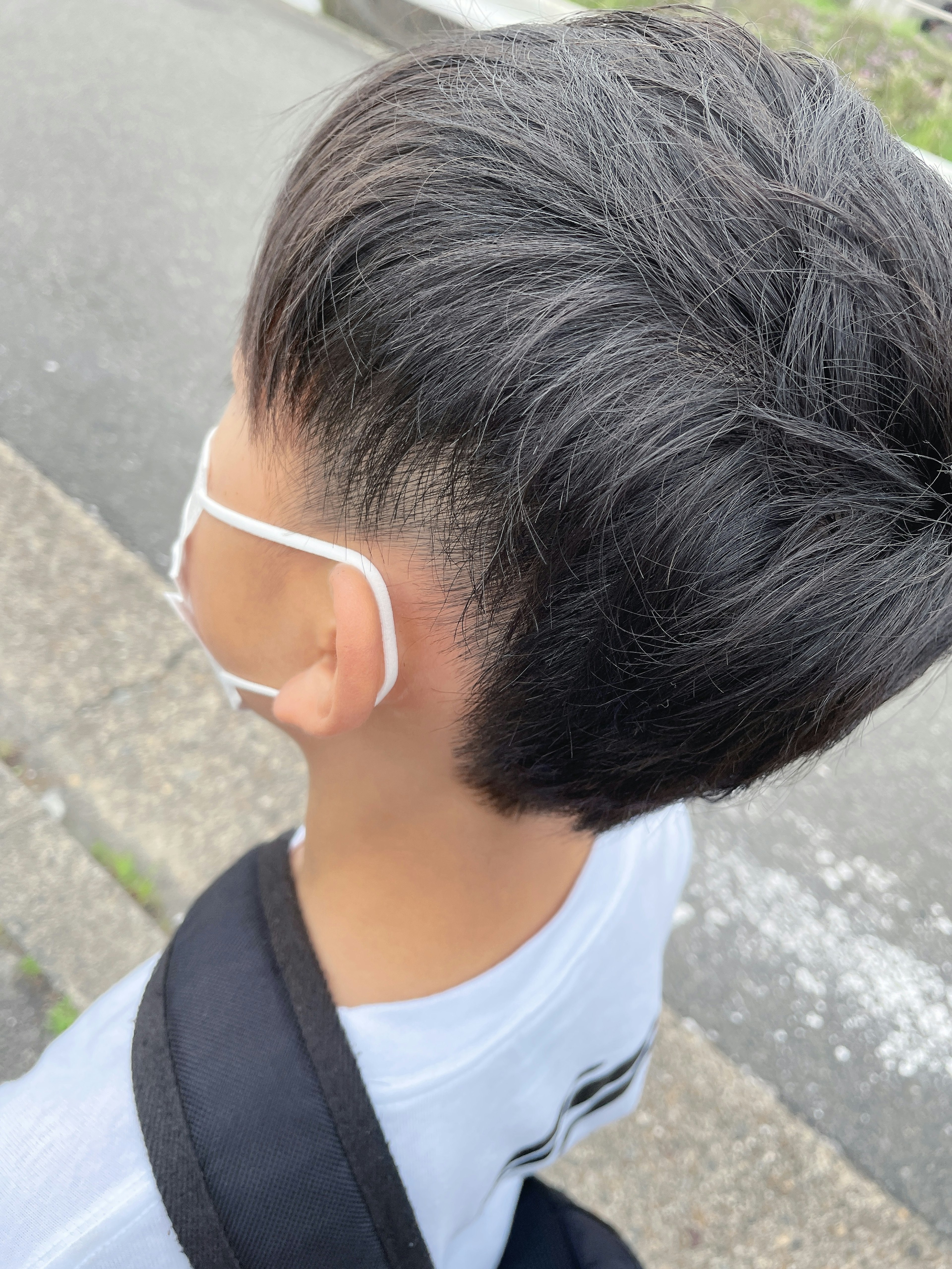 A child with a stylish haircut wearing a mask seen from behind