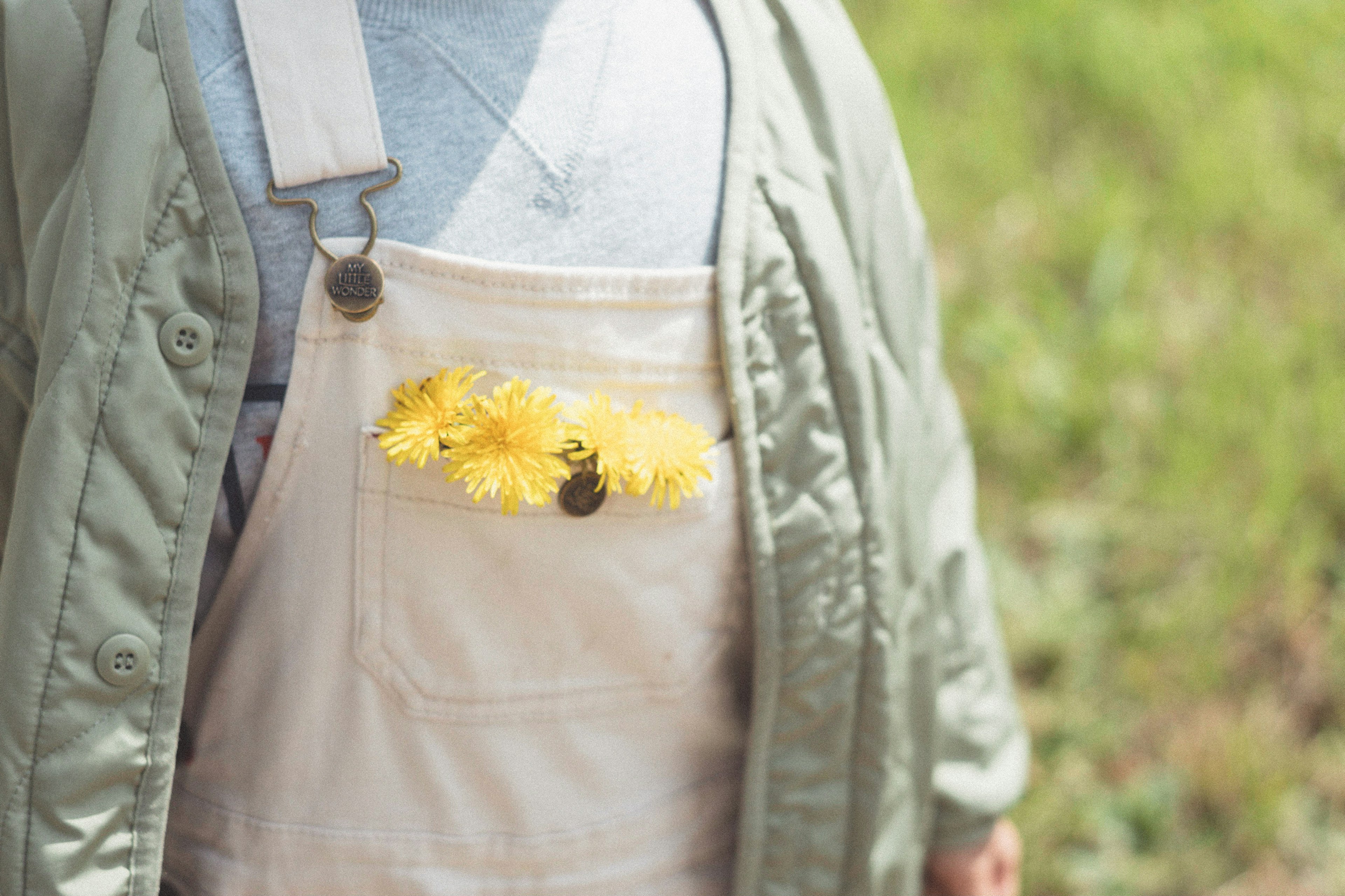 Person in Latzhose mit gelben Blumen in der Tasche