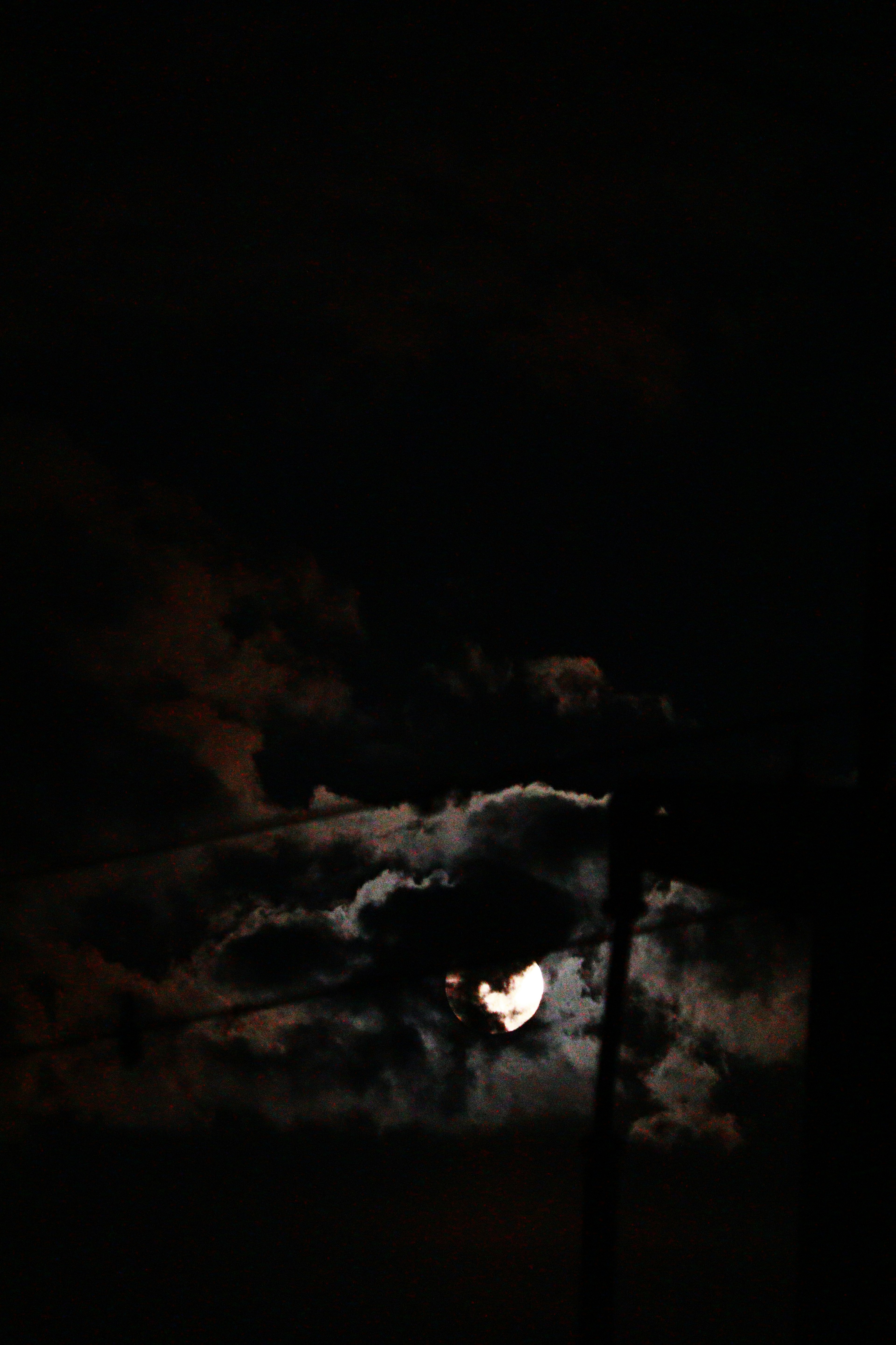 Moon partially obscured by clouds in a dark sky