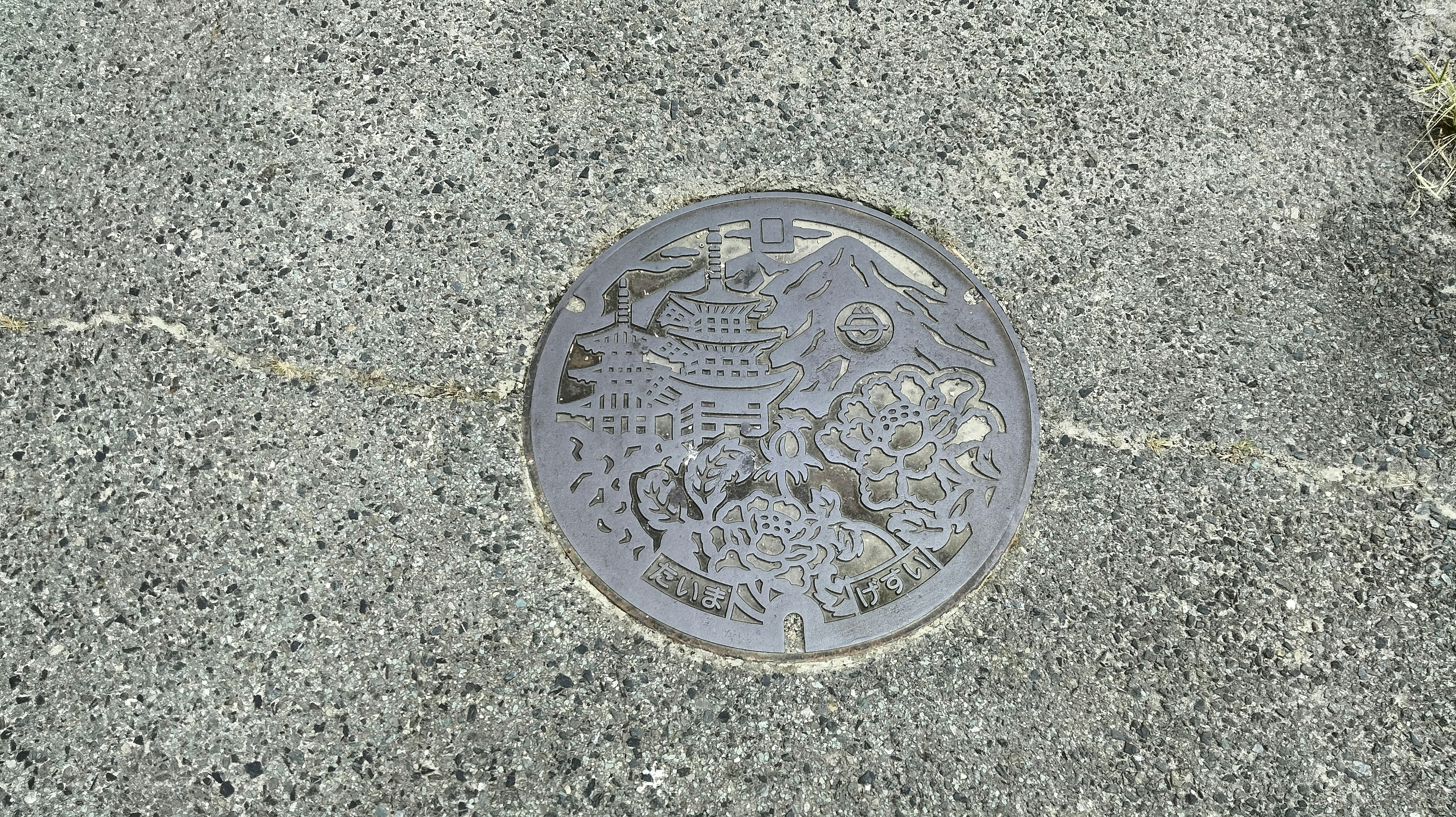 Round decorative manhole cover set in pavement