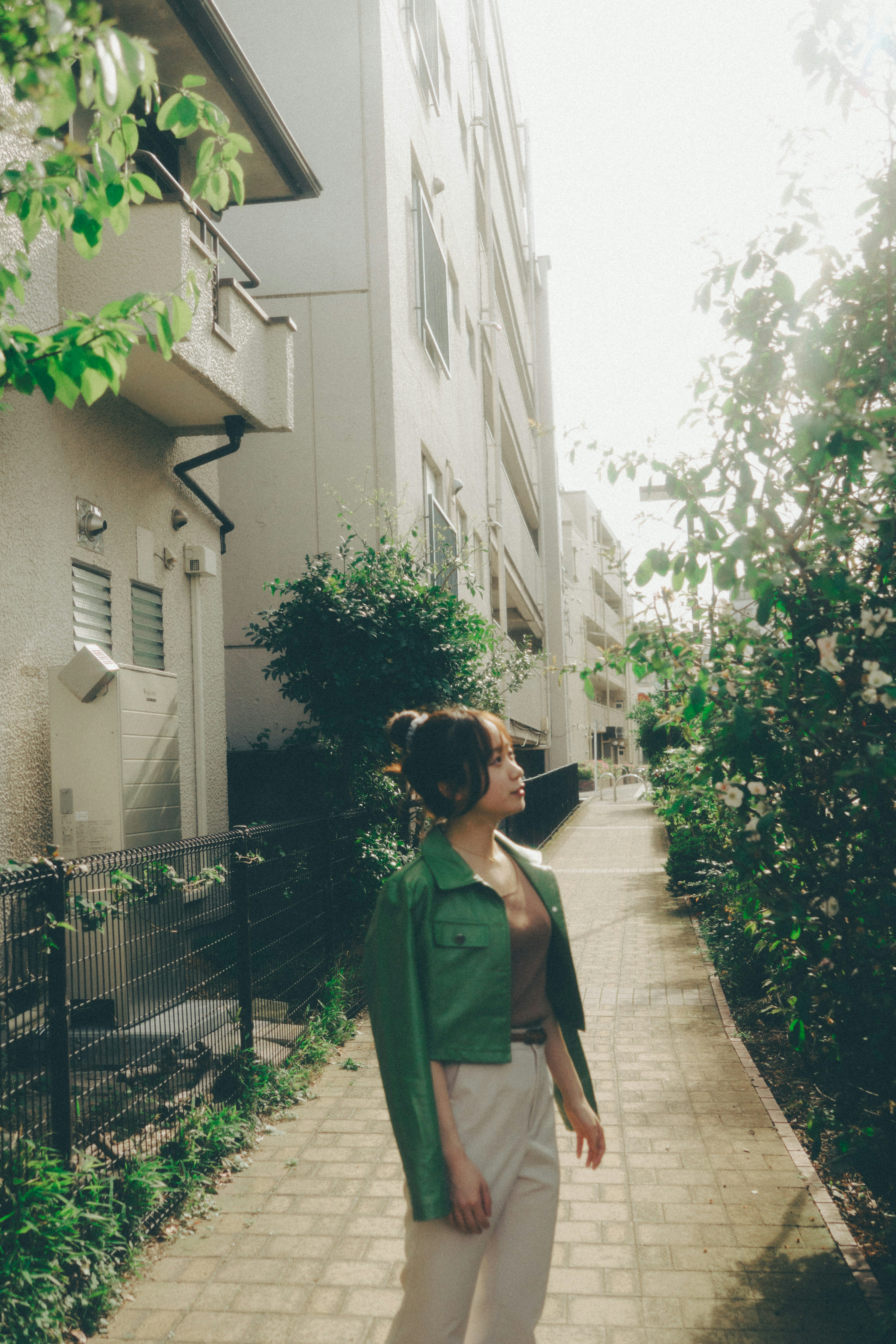 Woman in a green jacket walking along a path surrounded by greenery