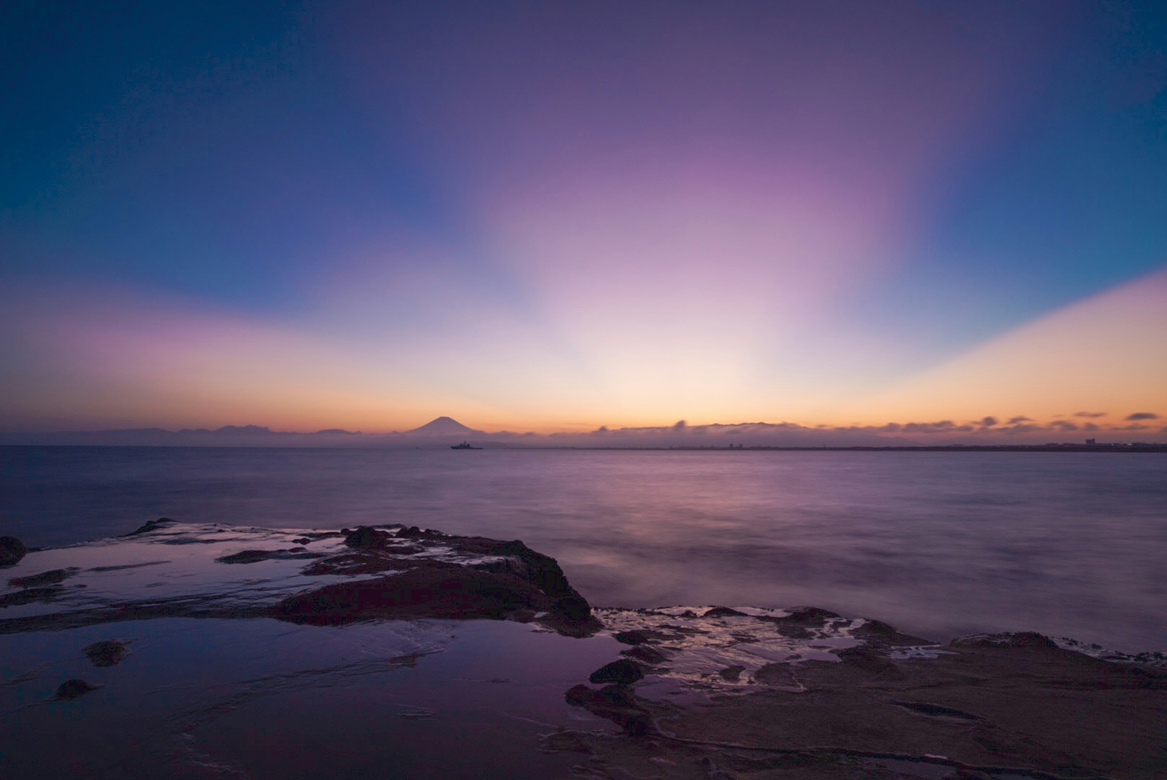 夕焼けの海岸風景で紫とオレンジのグラデーション空が広がる