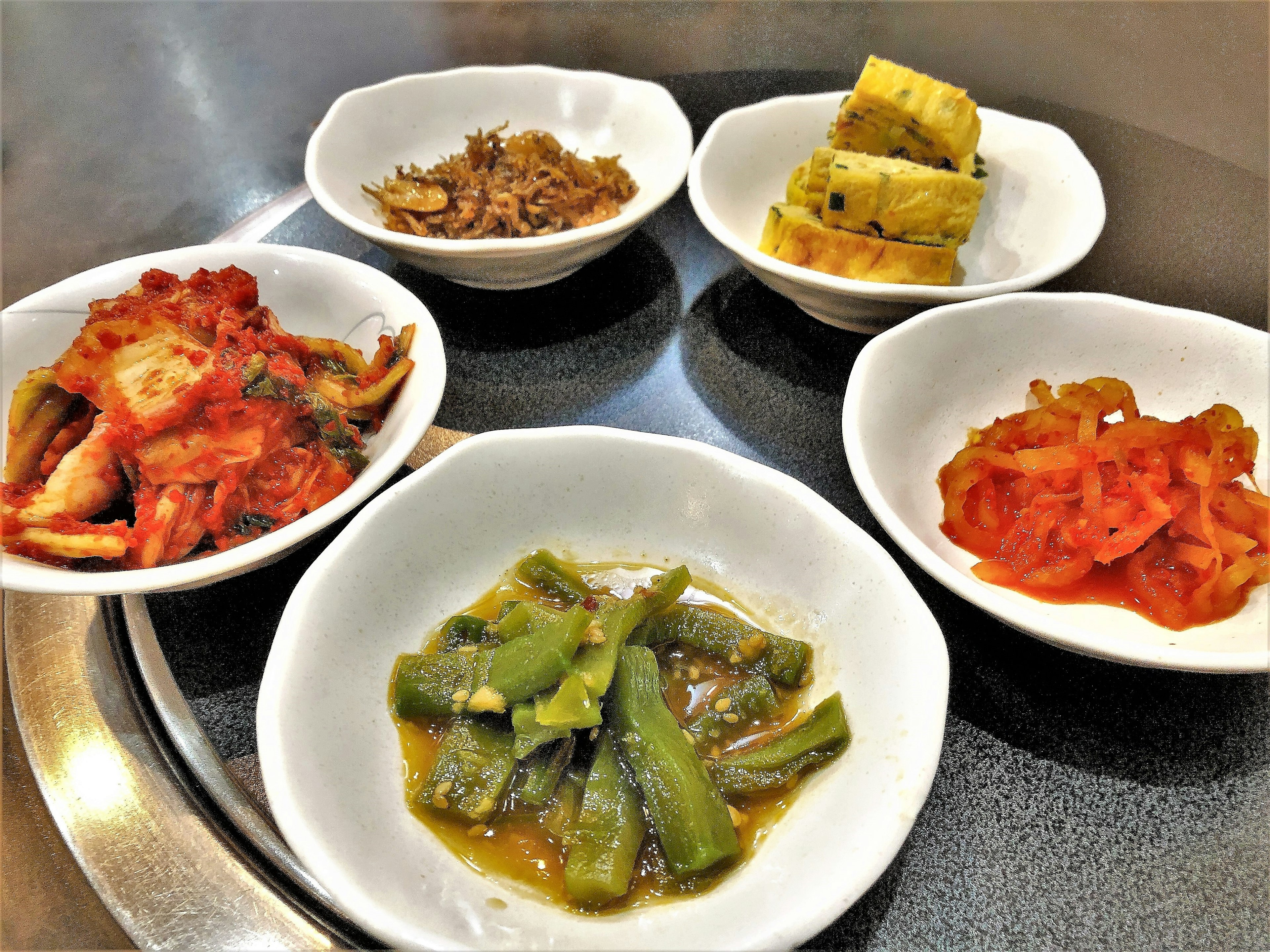 Assortment of Korean side dishes including kimchi and namul