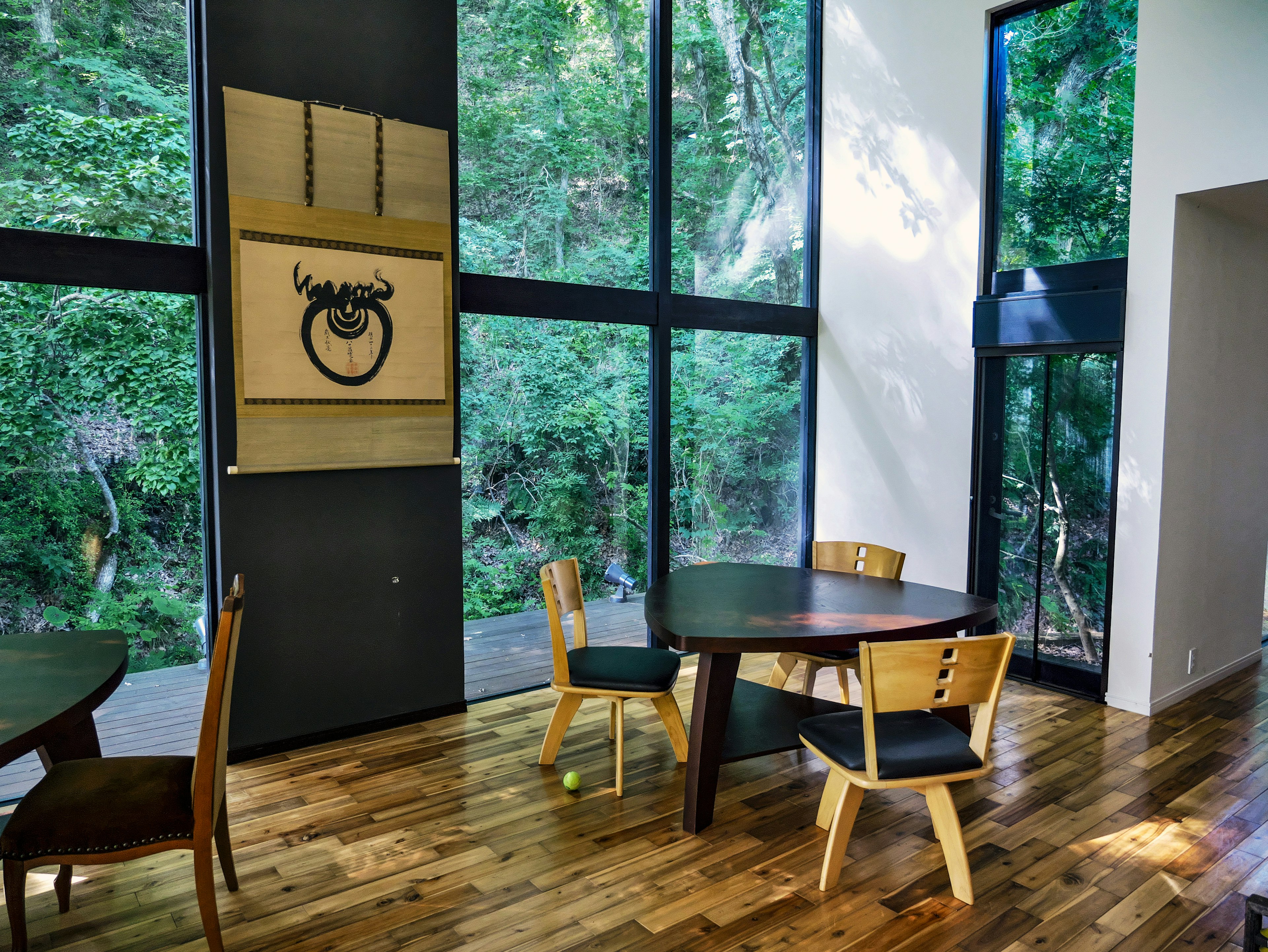 Comedor moderno con grandes ventanales que dan a un paisaje verde exuberante