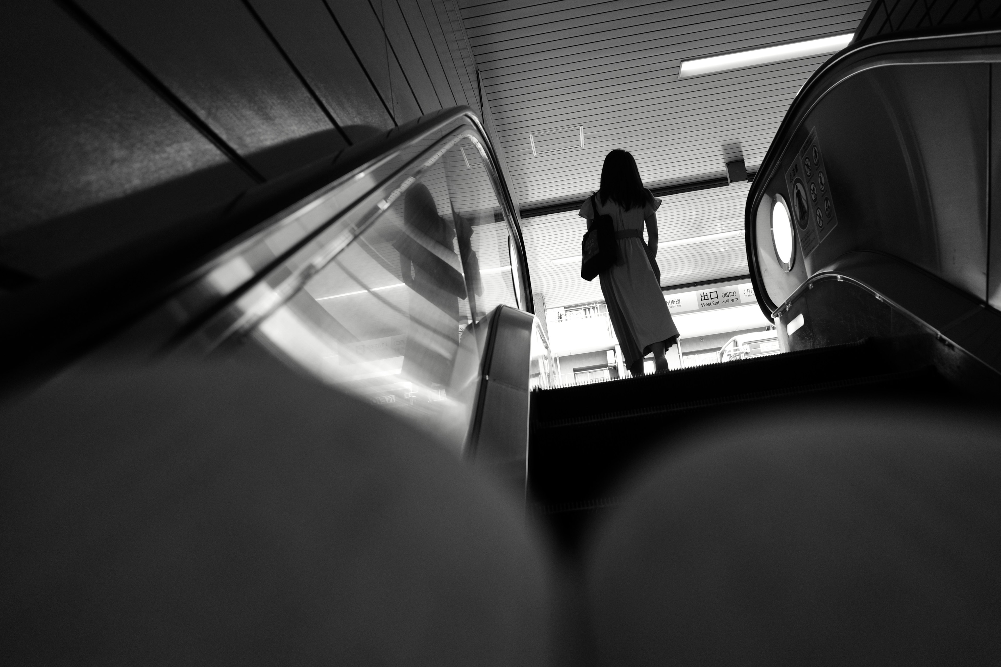 Silhouette d'une femme se tenant au sommet d'un escalator