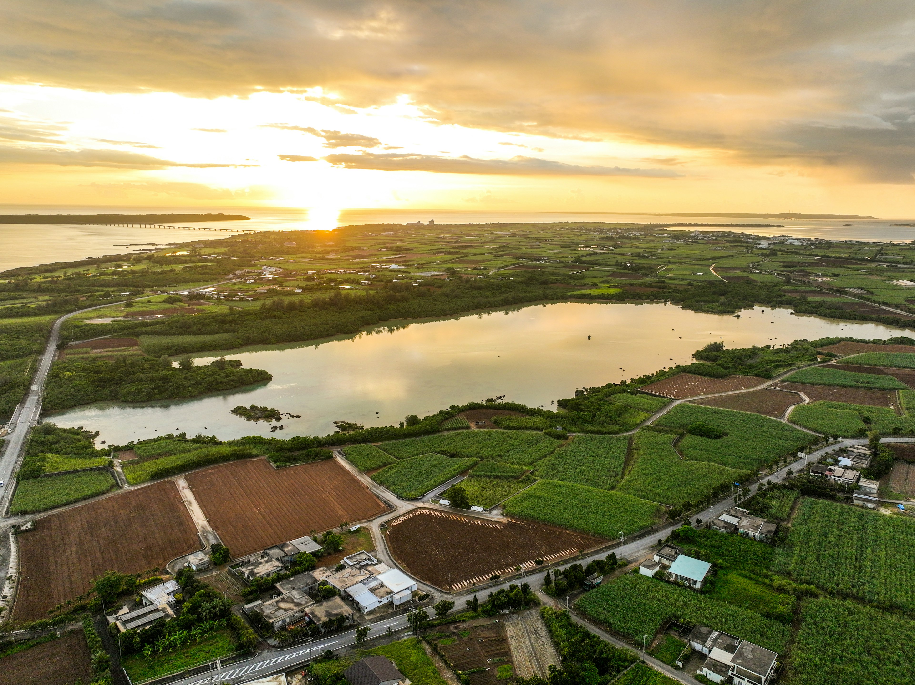 美しい夕日が湖に映る風景 緑豊かな農地と道路が広がる