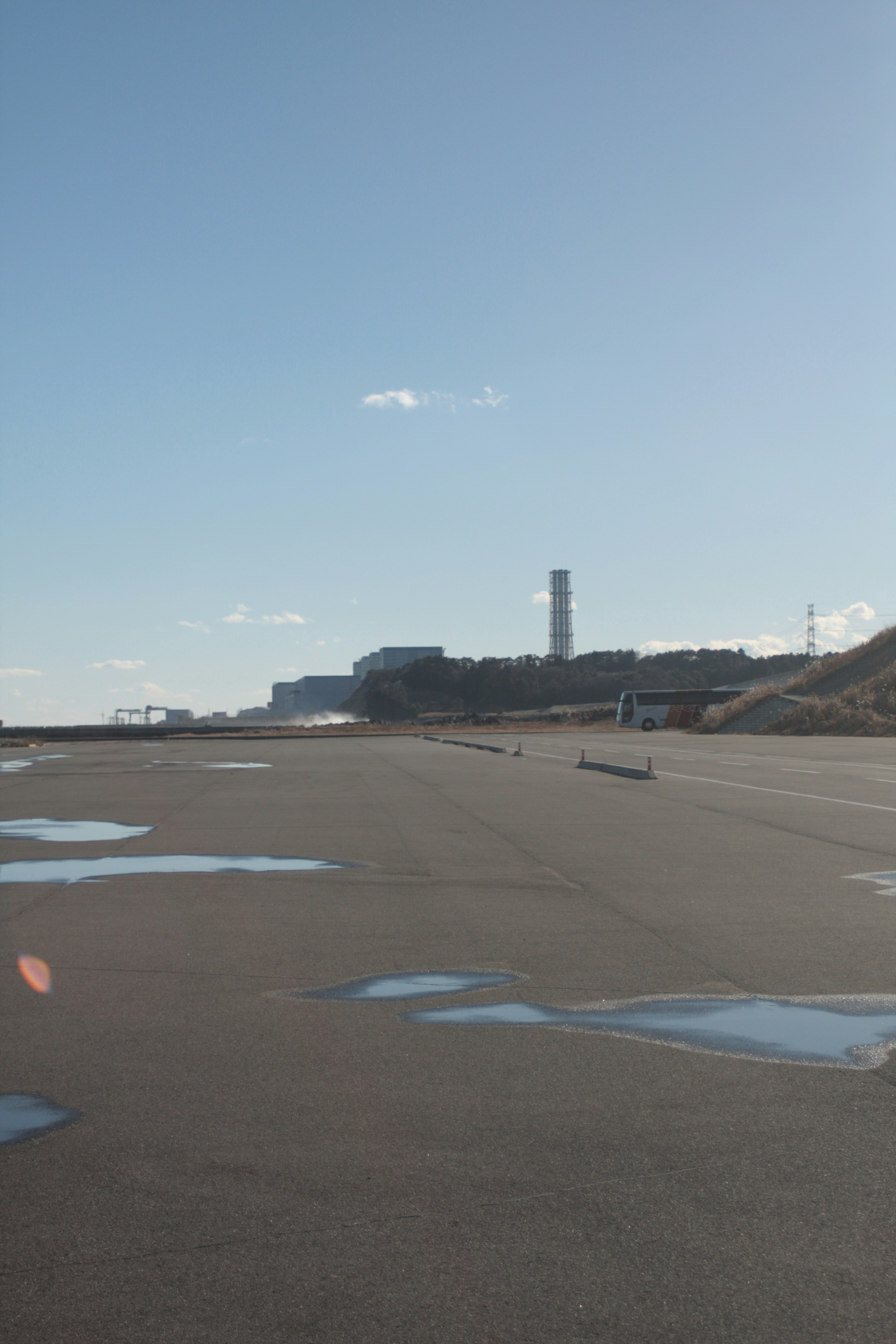 青空の下の広い舗装道路と遠くに見える工場