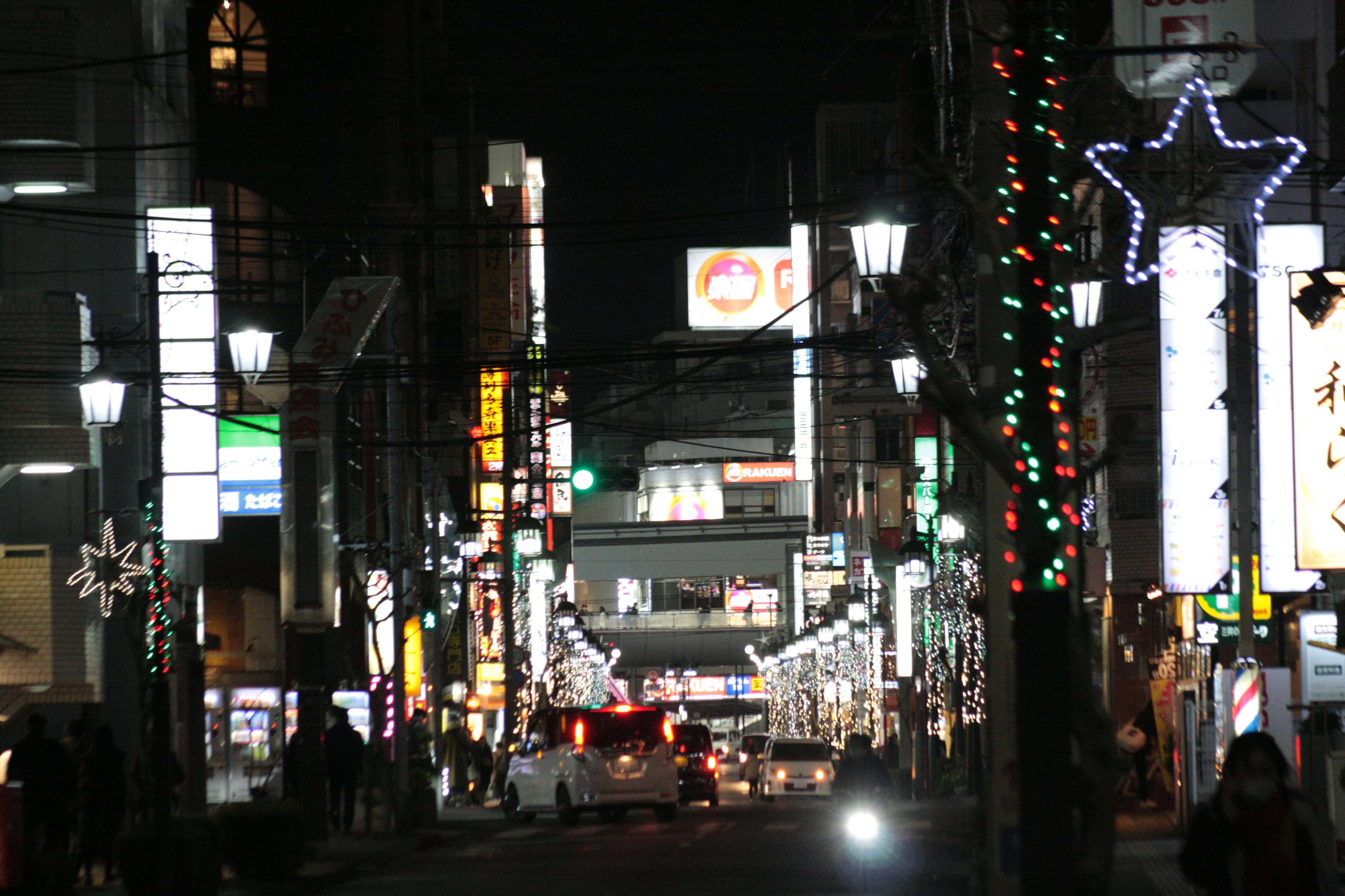 Night street scene with illuminated decorations and pedestrians